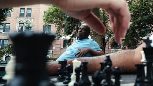 Chess player watching an opponent’s move across the board in a public park.