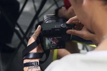 Photographer Billy Dinh reviews images on a Leica Q camera display after capturing candid street photography in a New York City park.