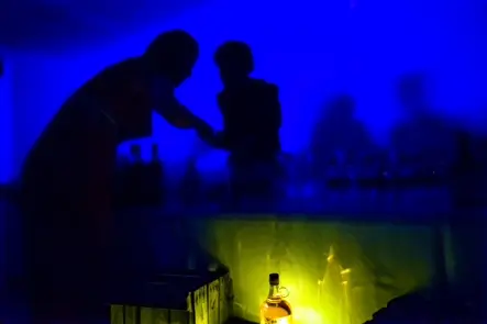 Documentary photograph of silhouetted guests interacting in blue ambient light at a nighttime gathering, capturing mood, human connection, and contemporary nightlife.