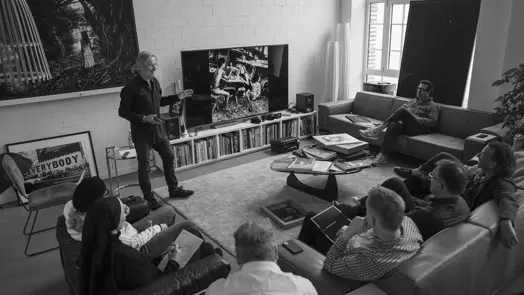 A photographer presents his work to a group of participants in a studio.
