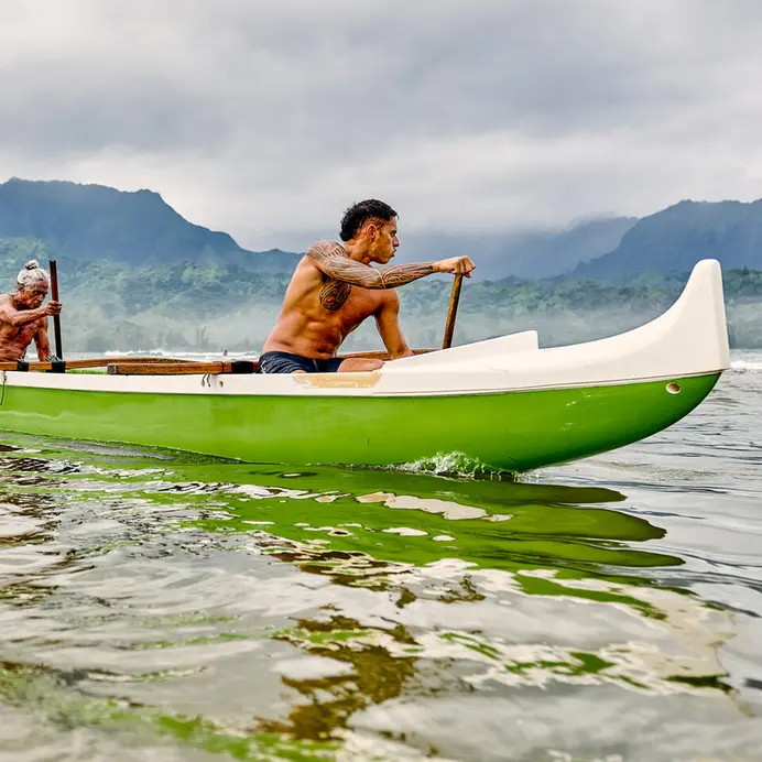 Hawaiian men in a green canoe