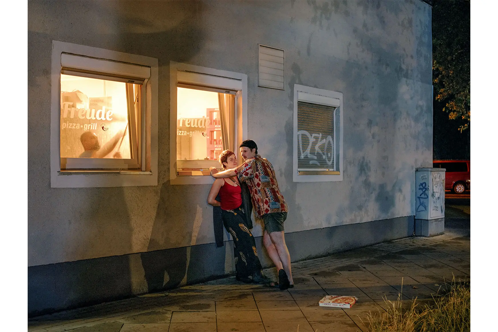 Two young adults standing in front of pizza shop