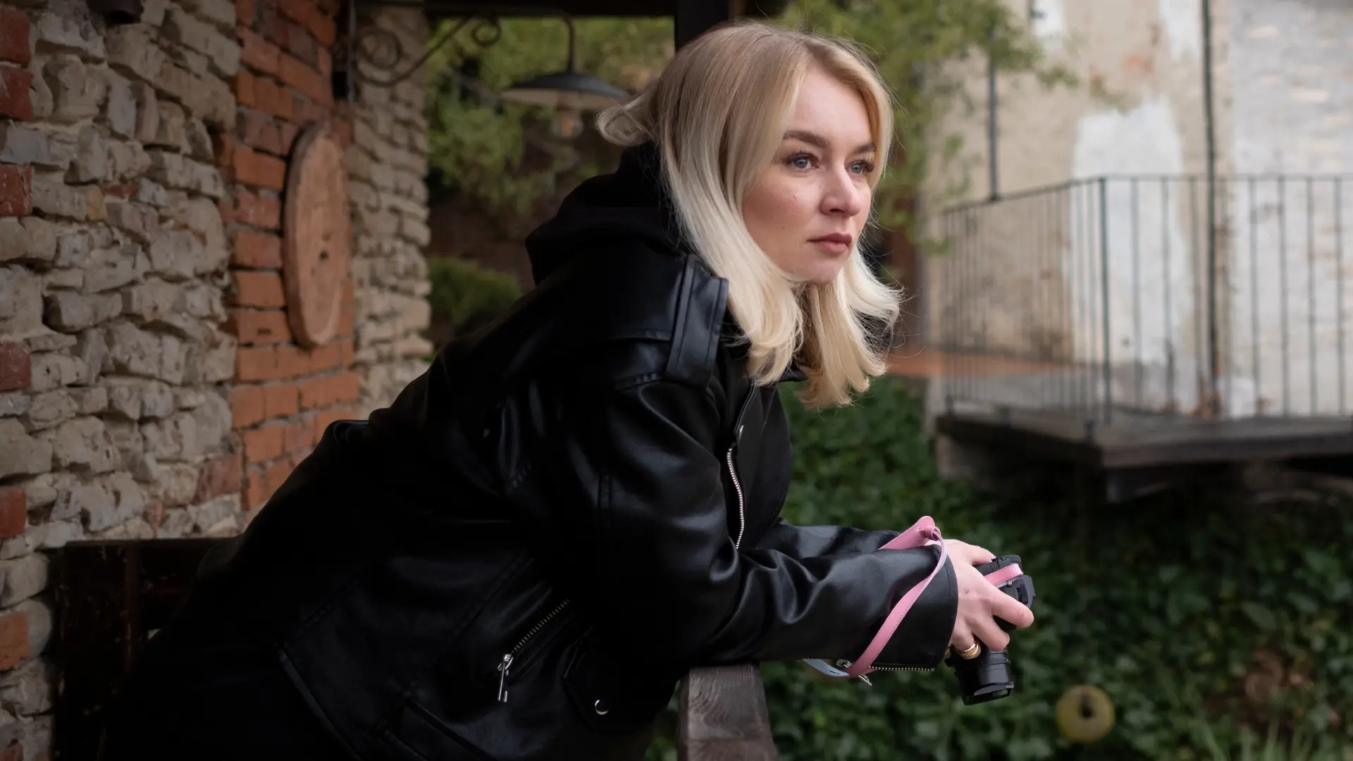 Woman on a balcony holding a camera in her hands.