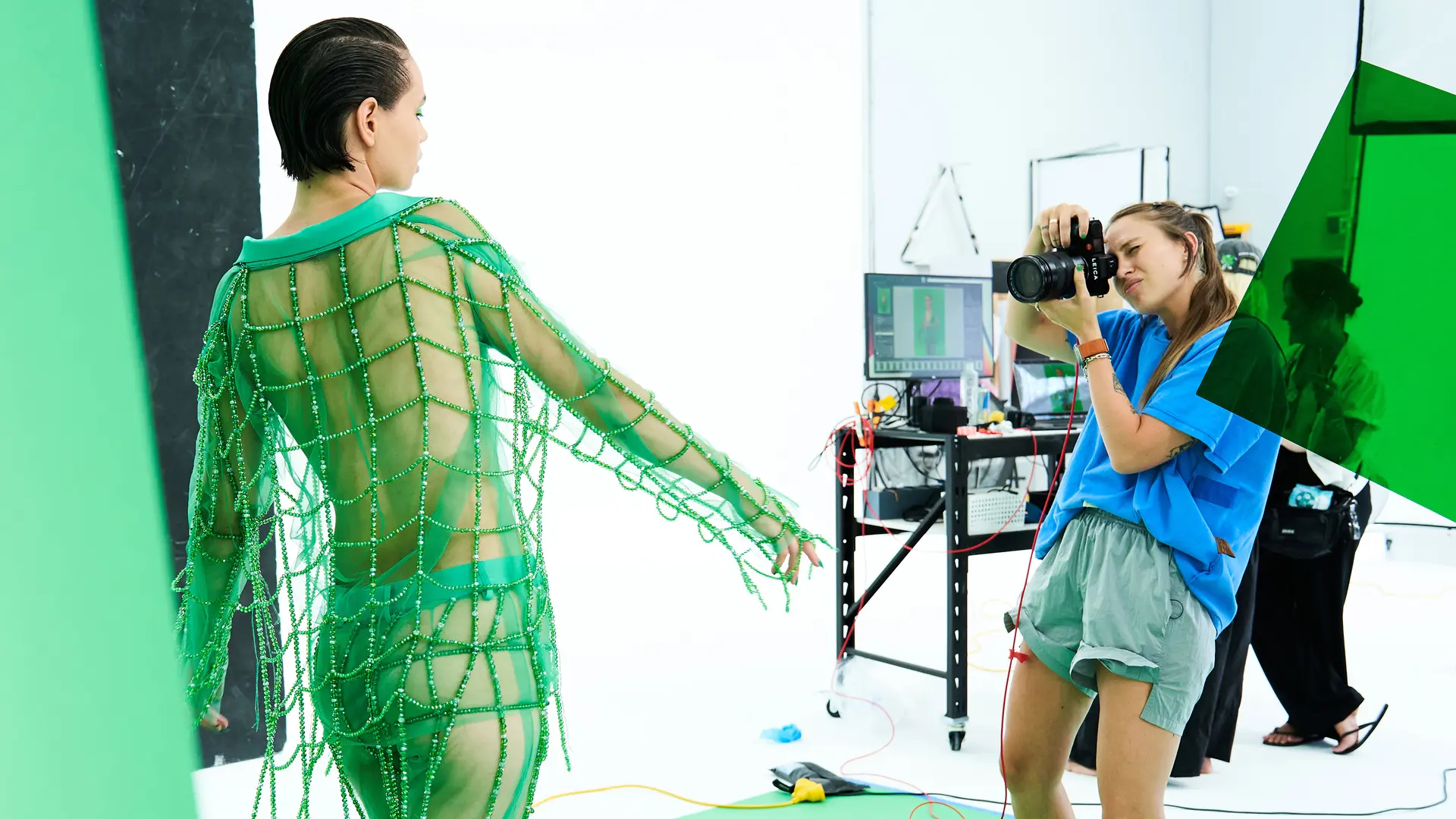 Photographer takes a picture in a studio of a model in a green net outfit.