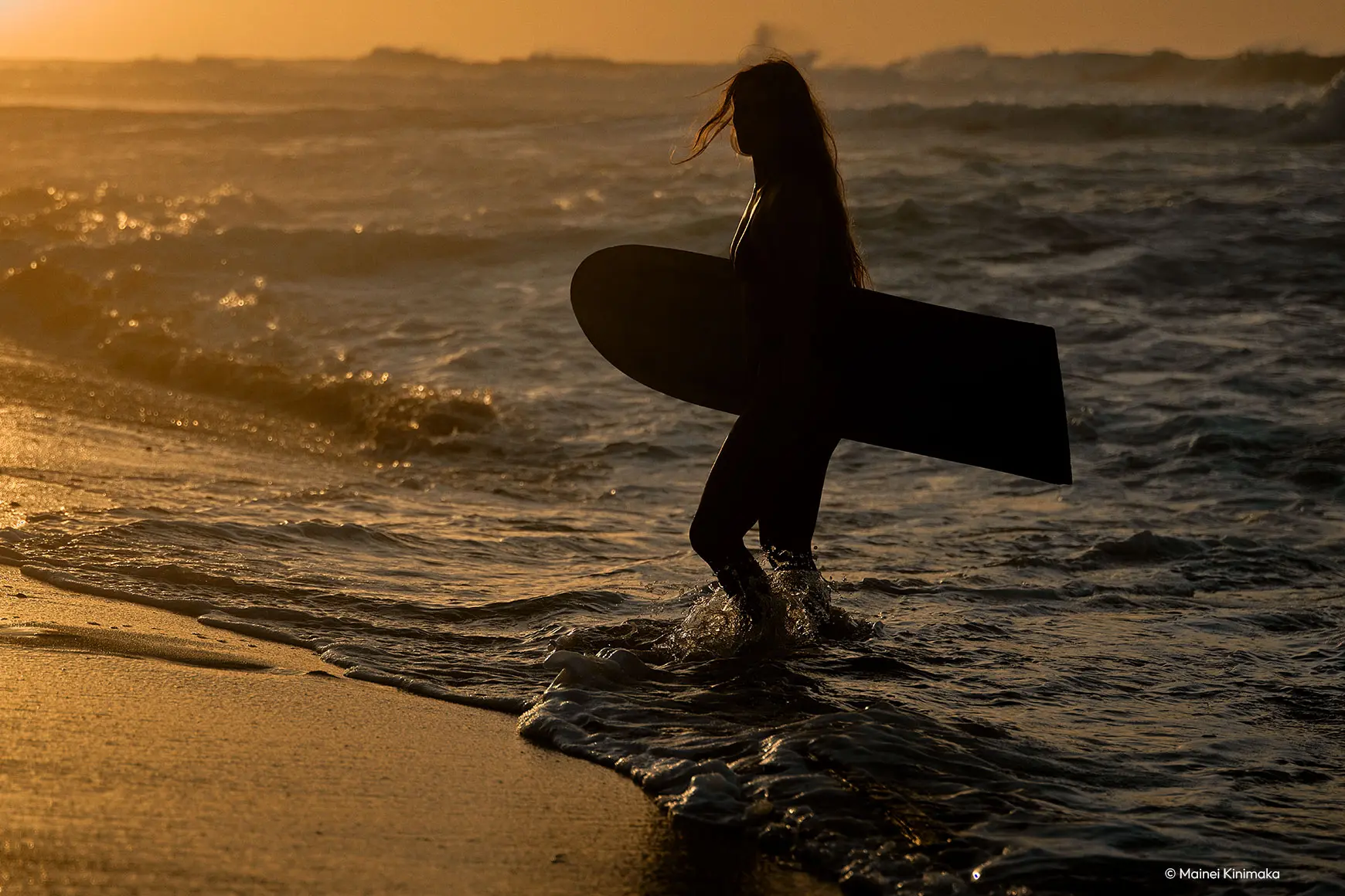 Woman standing with board in the sea