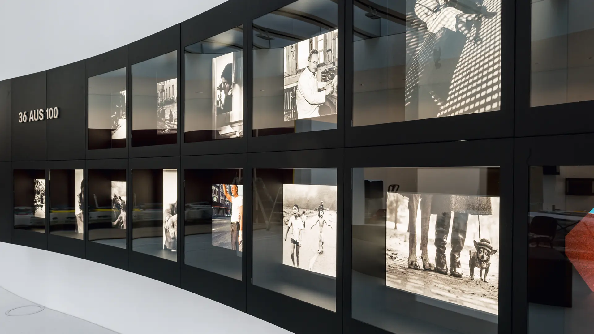 An exhibition of black and white photographs of famous events, presented in two curved rows.
