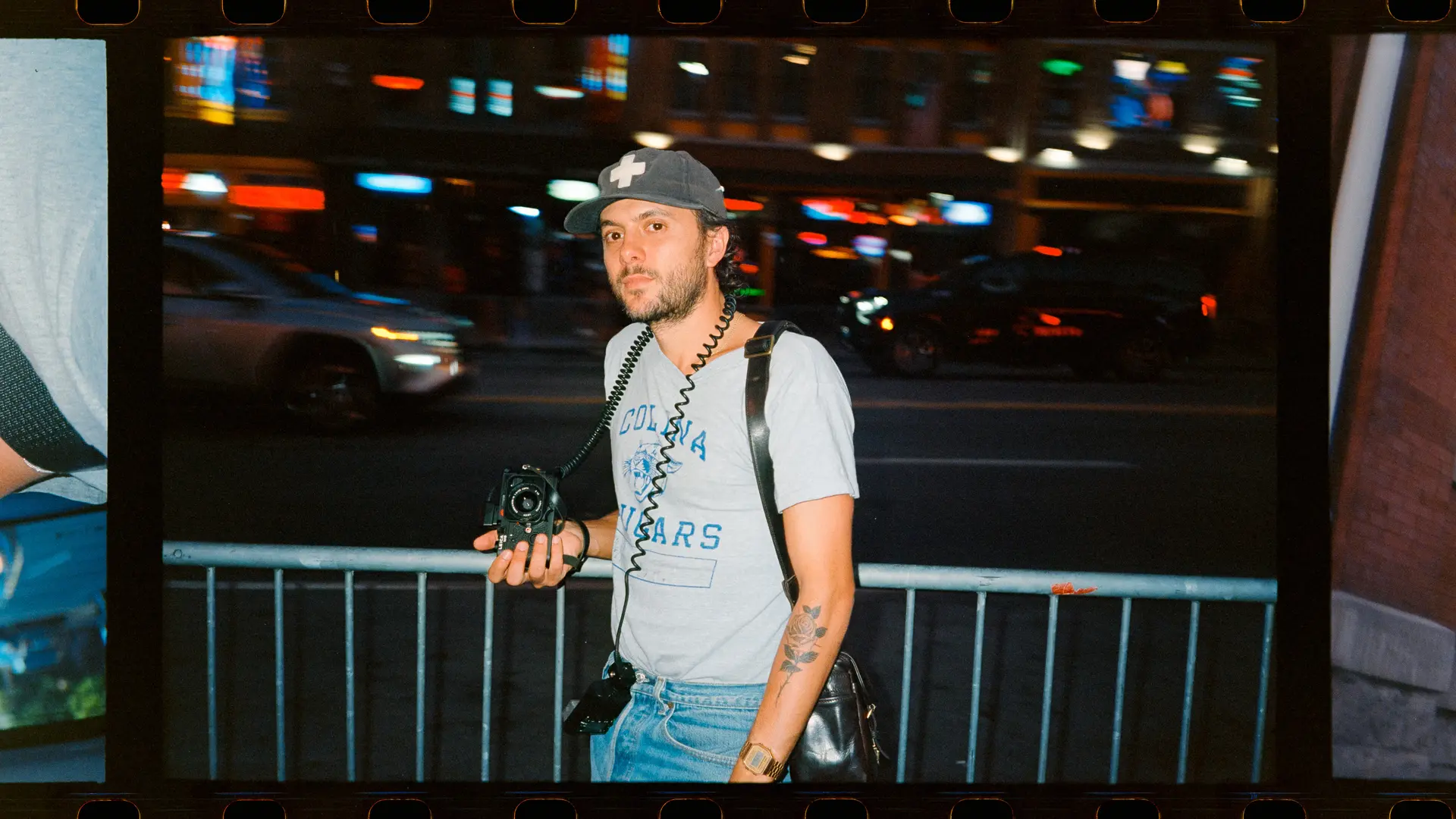 Joe Greer with a Leica M6 in his hand standing at a street at night.