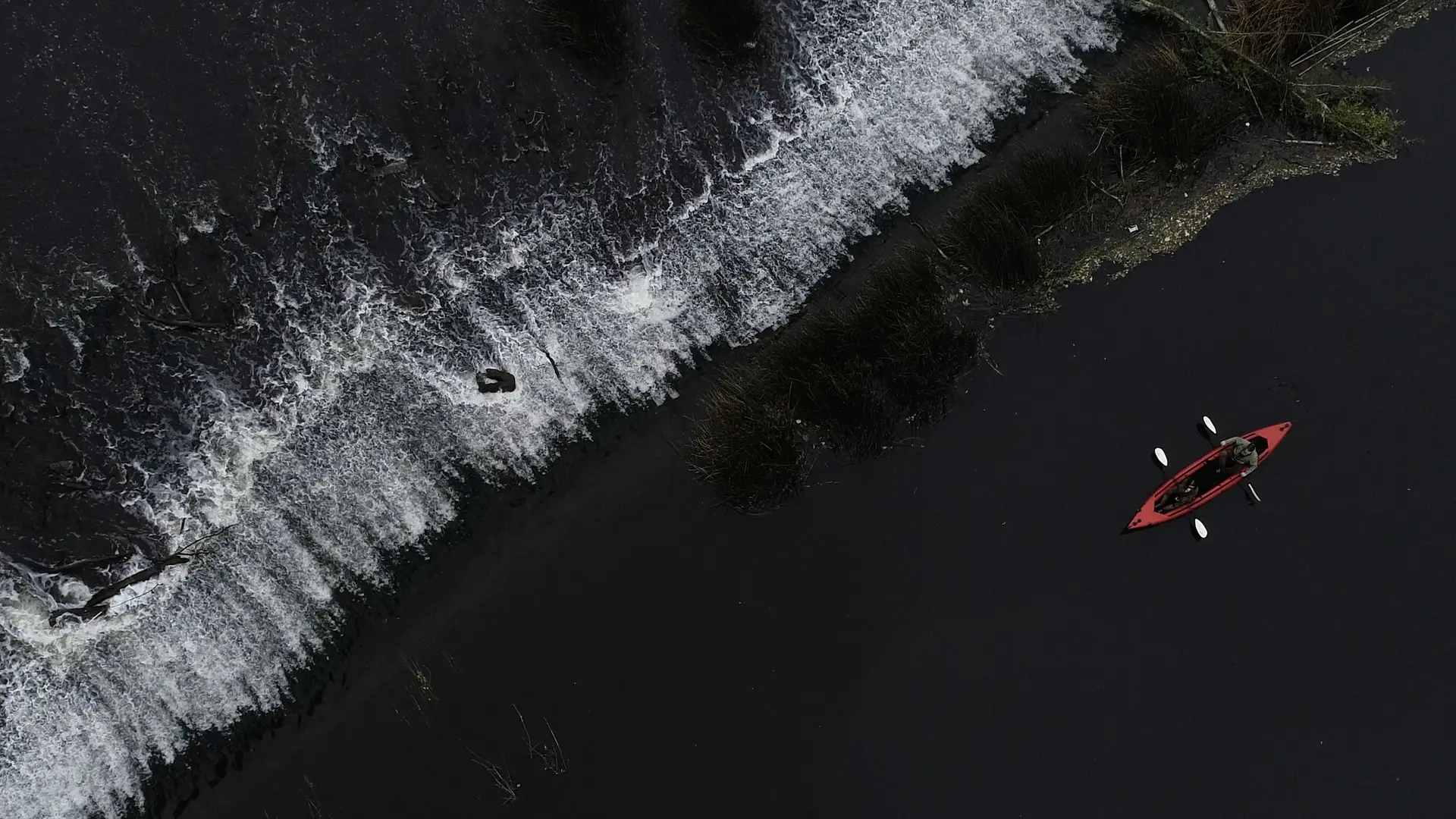 Red canoe paddling along the black sea coast.