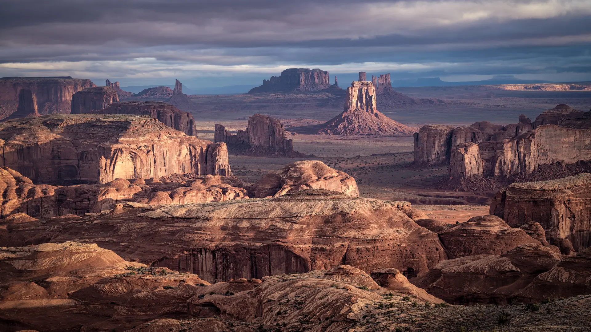 Vast desert landscape with remarkable rock formations under a cloudy sky.