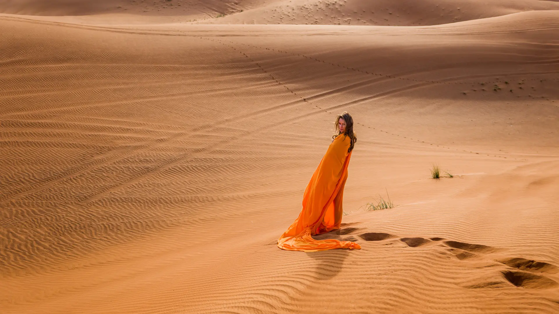 Woman in an orange dress standing in the desert.