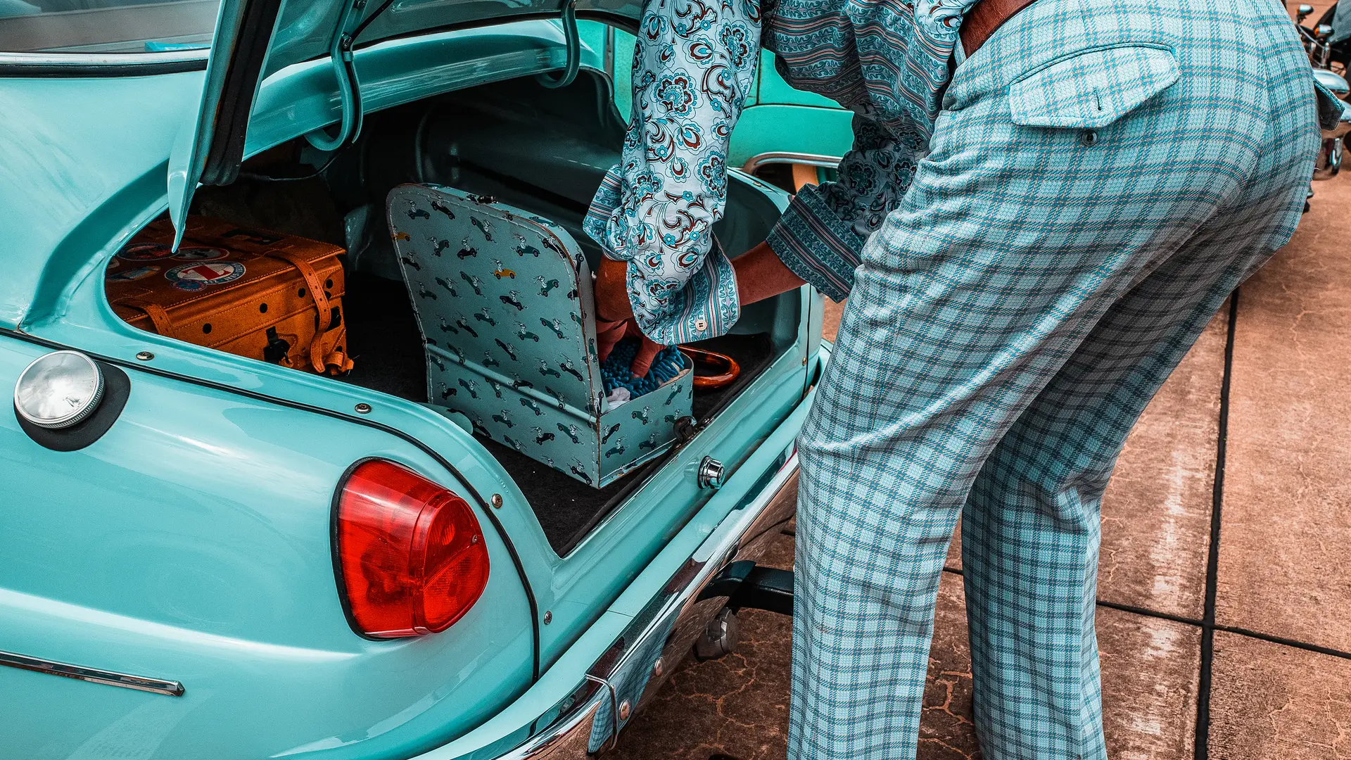 Man in turquoise clothes in front of turquoise car 