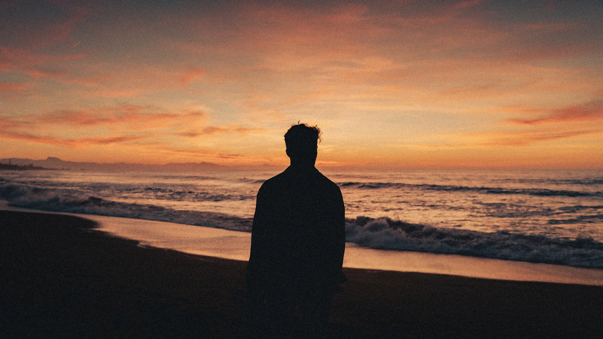 Silhouette of a man watching the sunset on the beach.