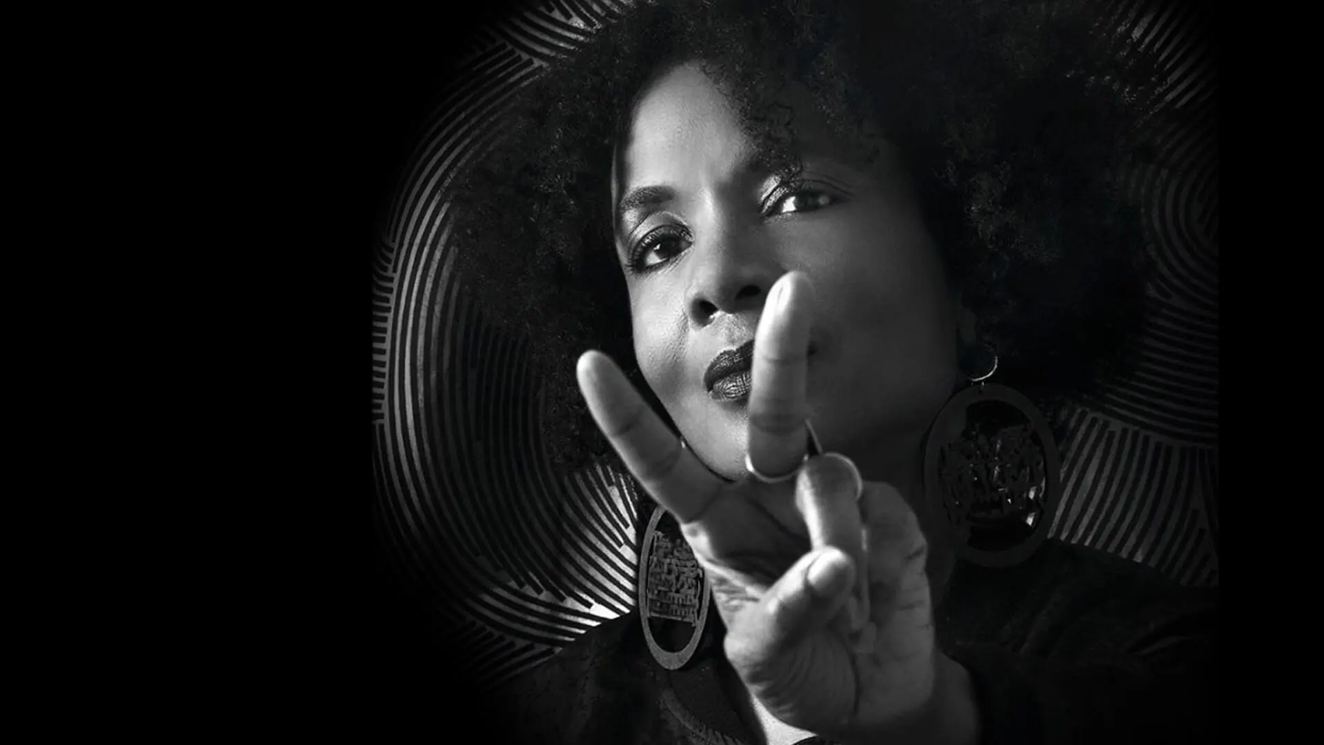 Black and white portrait of a woman with an Afro hairstyle making the peace sign