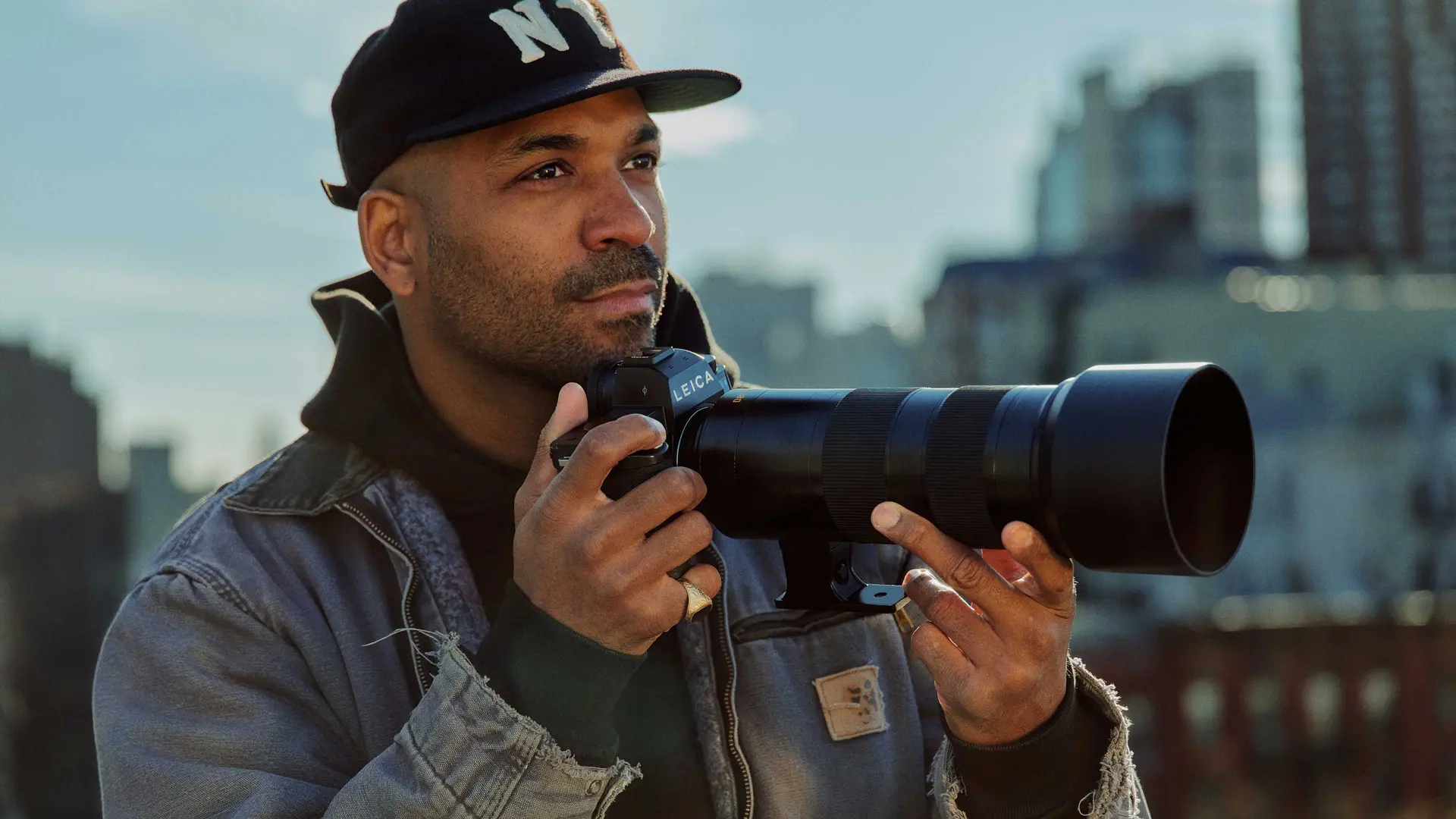 A young man is taking pictures with a cityscape in the background