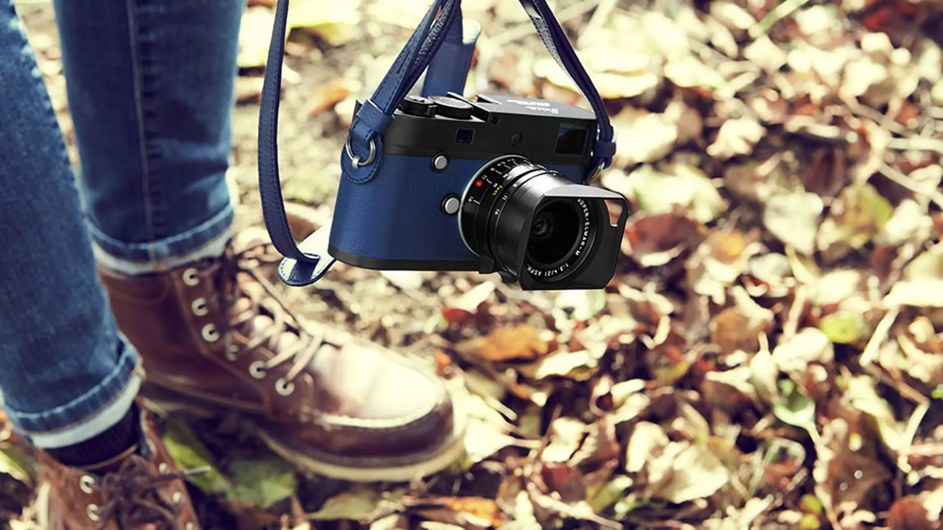 Man in the fall leaves with blue leica camera