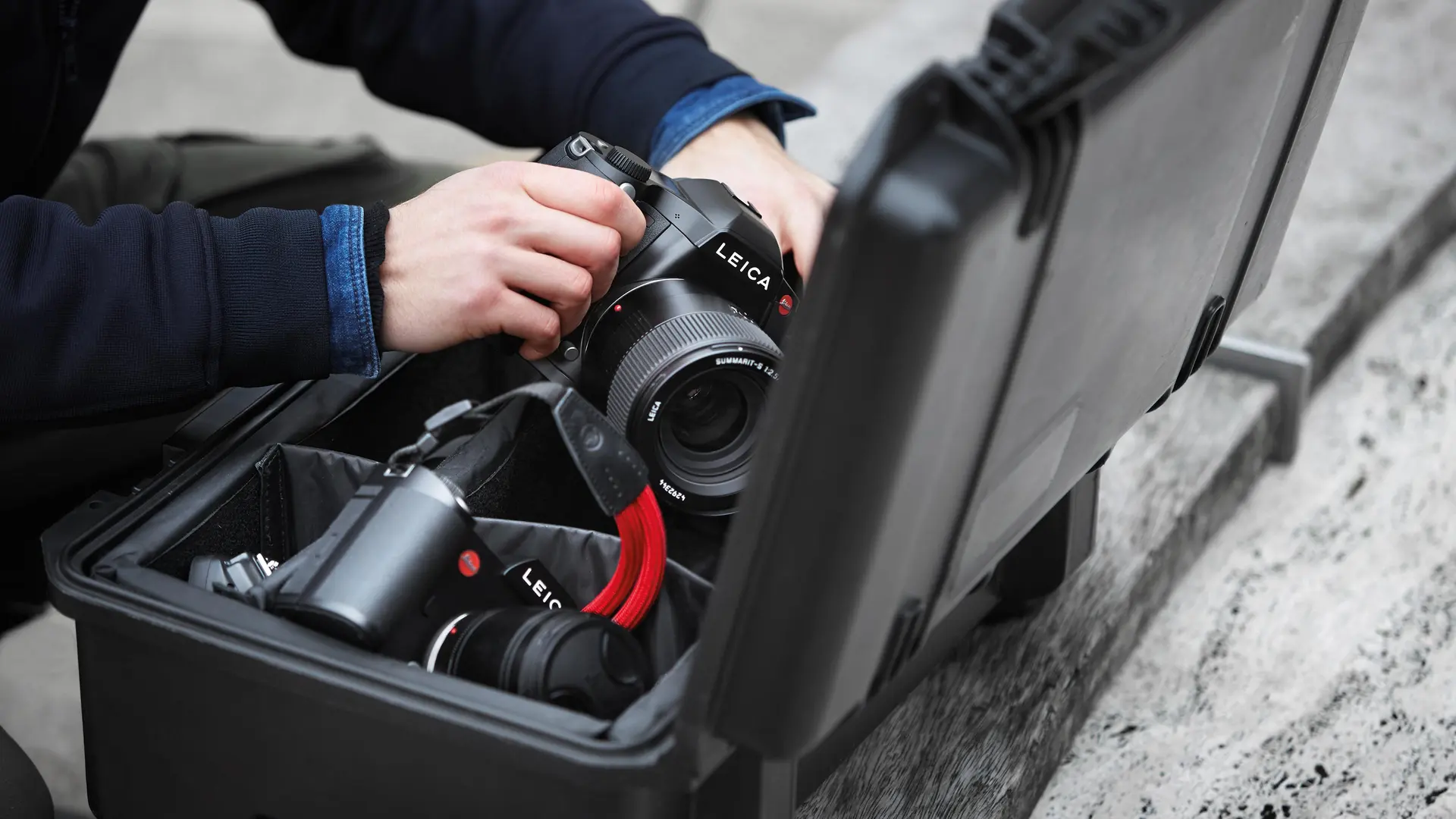Close-up of a person taking a Leica camera out of a camera case