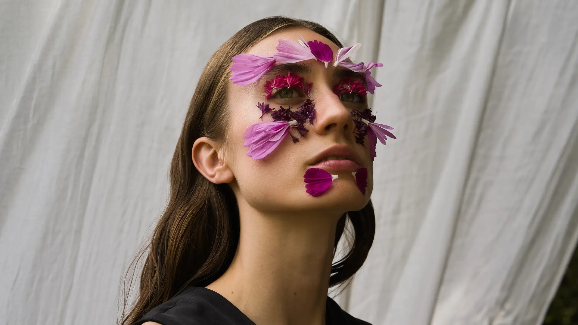 Ein Portrait einer Frau mit Blumen auf ihrem Gesicht.