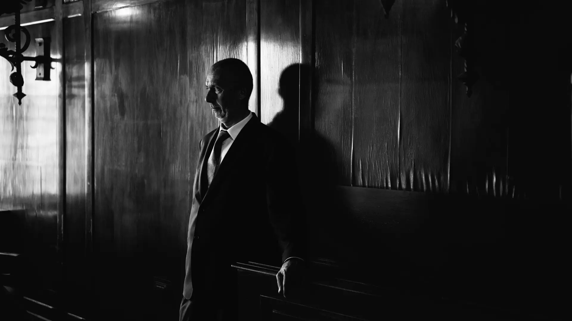 Black and White image of man leaning against a wall