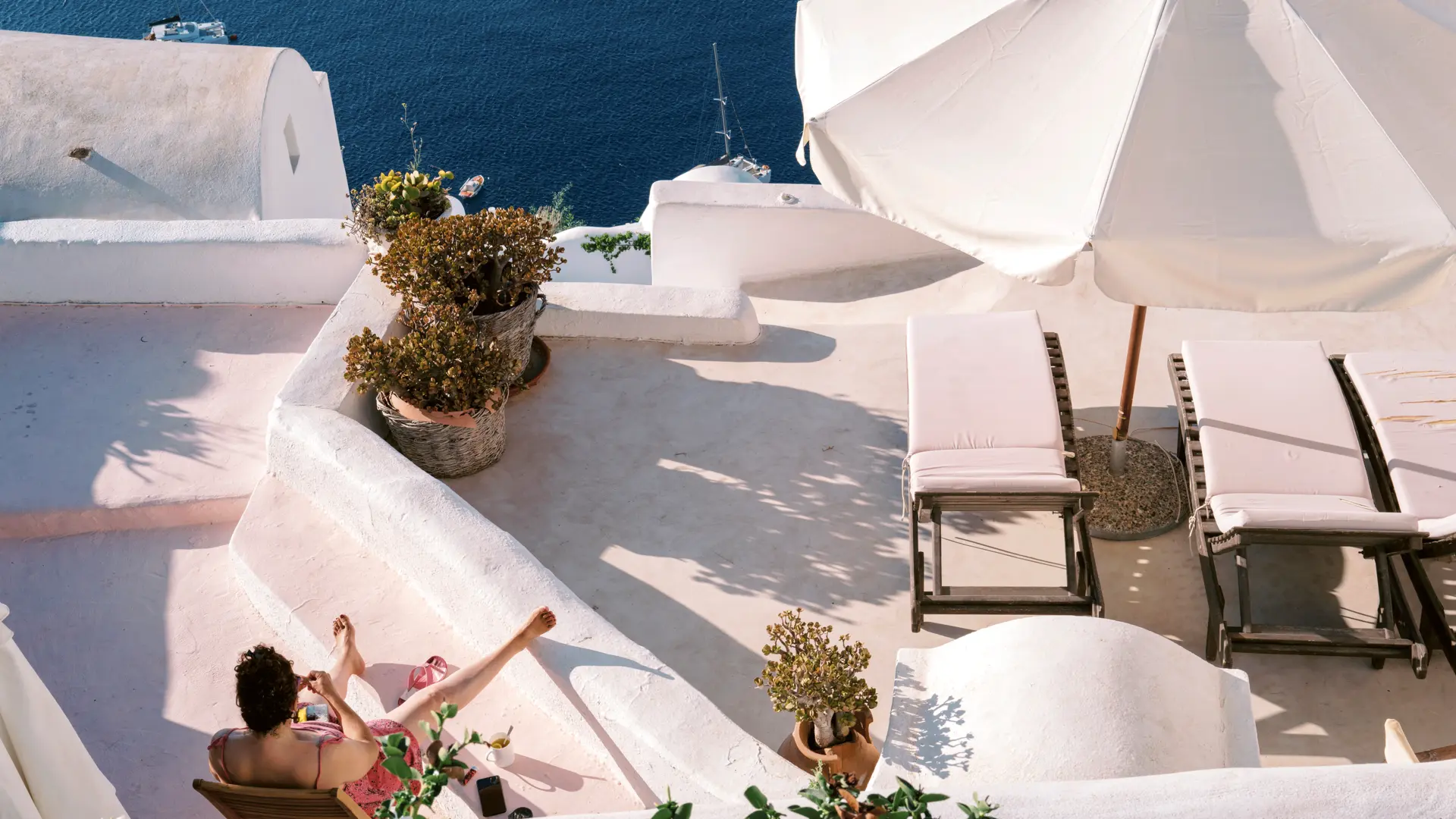 Photograph of a lady lounging on a balcony looking out to sea.