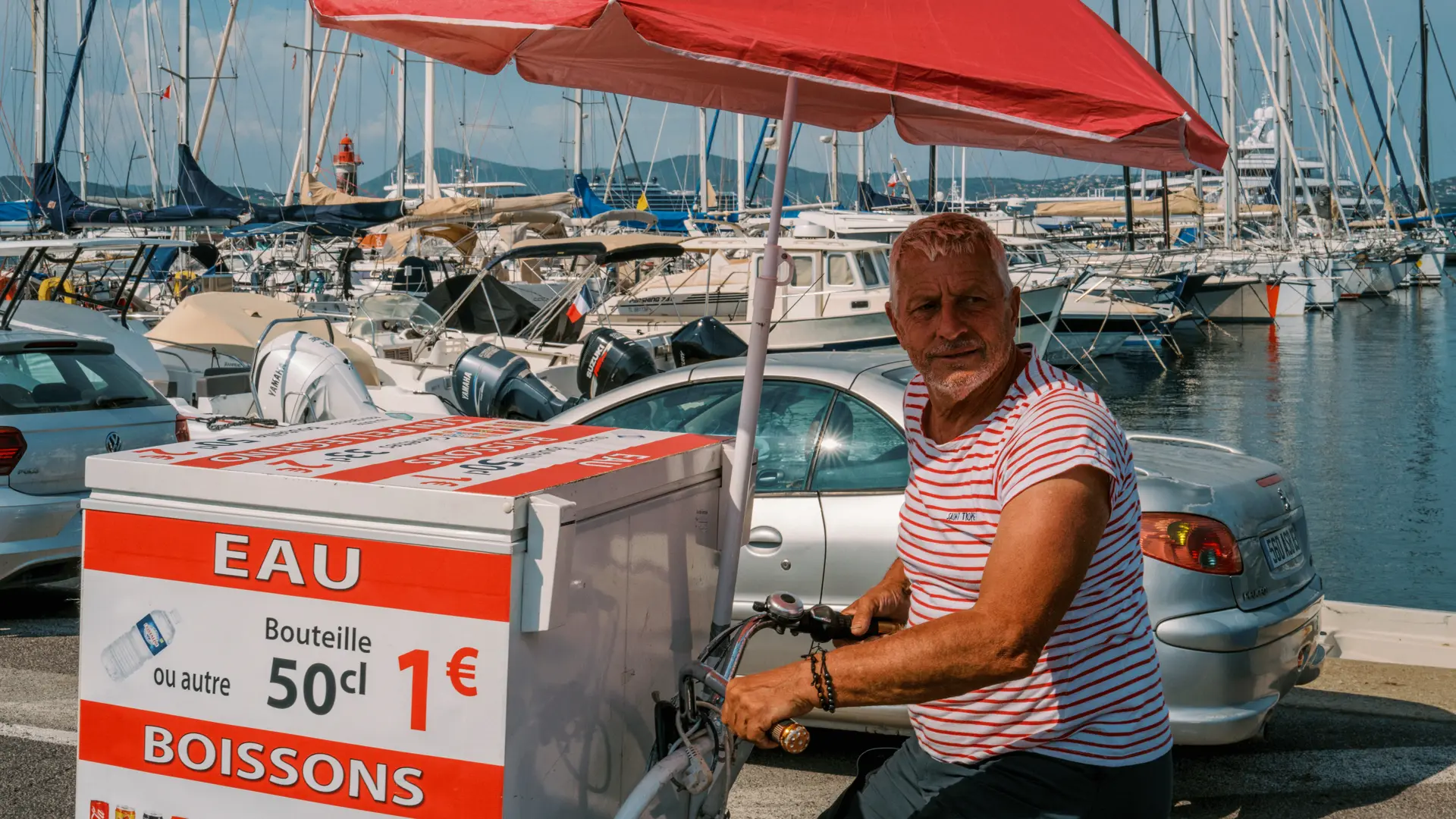 Image of a vendor on sitting on his bike by a marina.