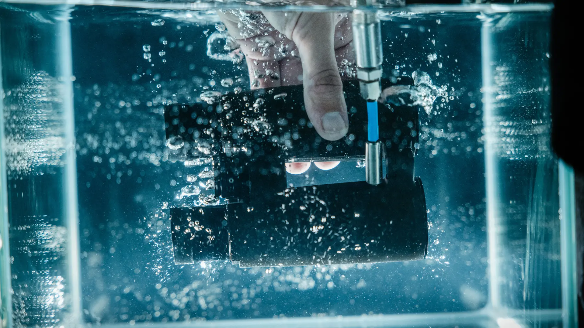 A worker dipping a pair of Leica binoculars under water