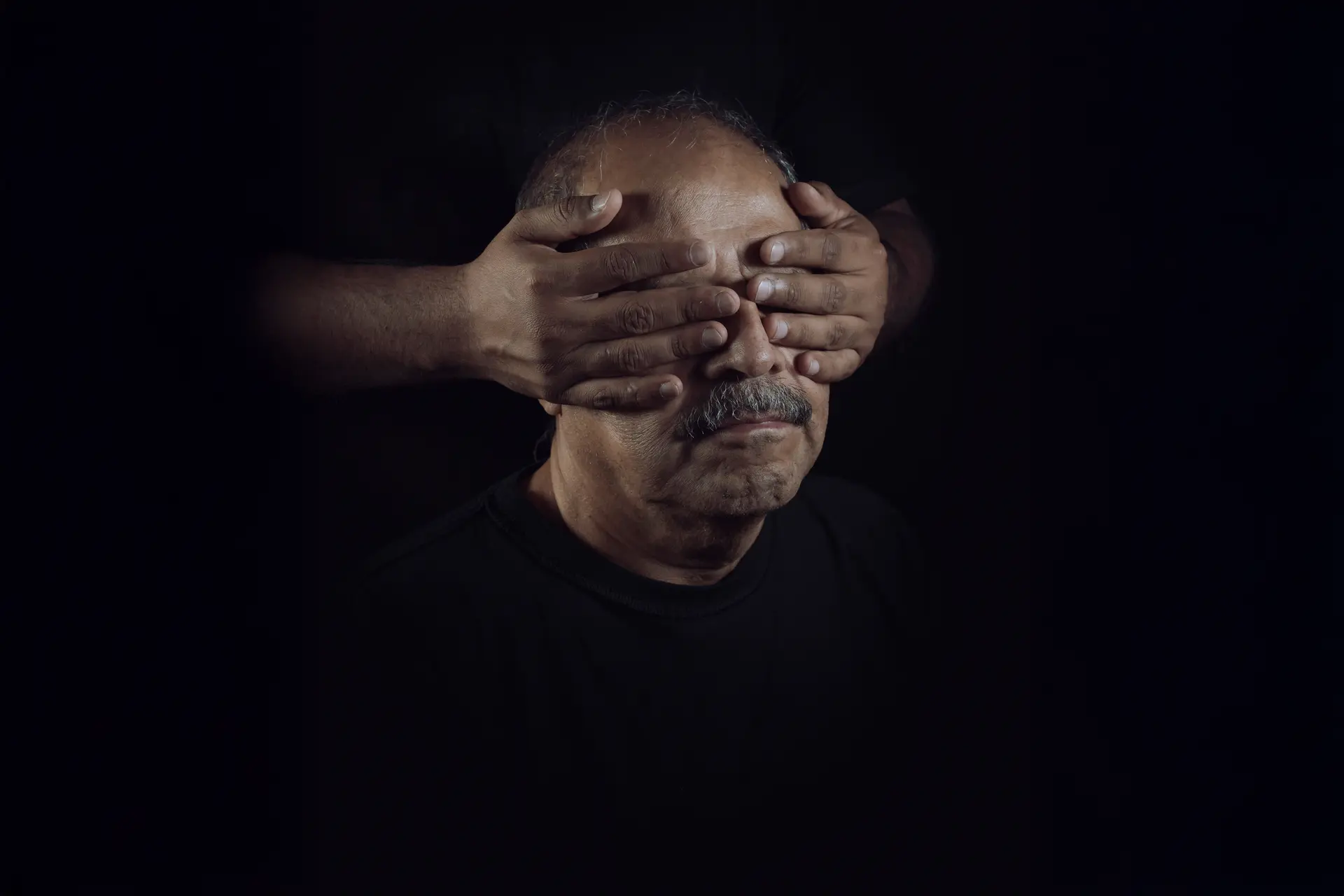 Hands cover man's eyes from behind