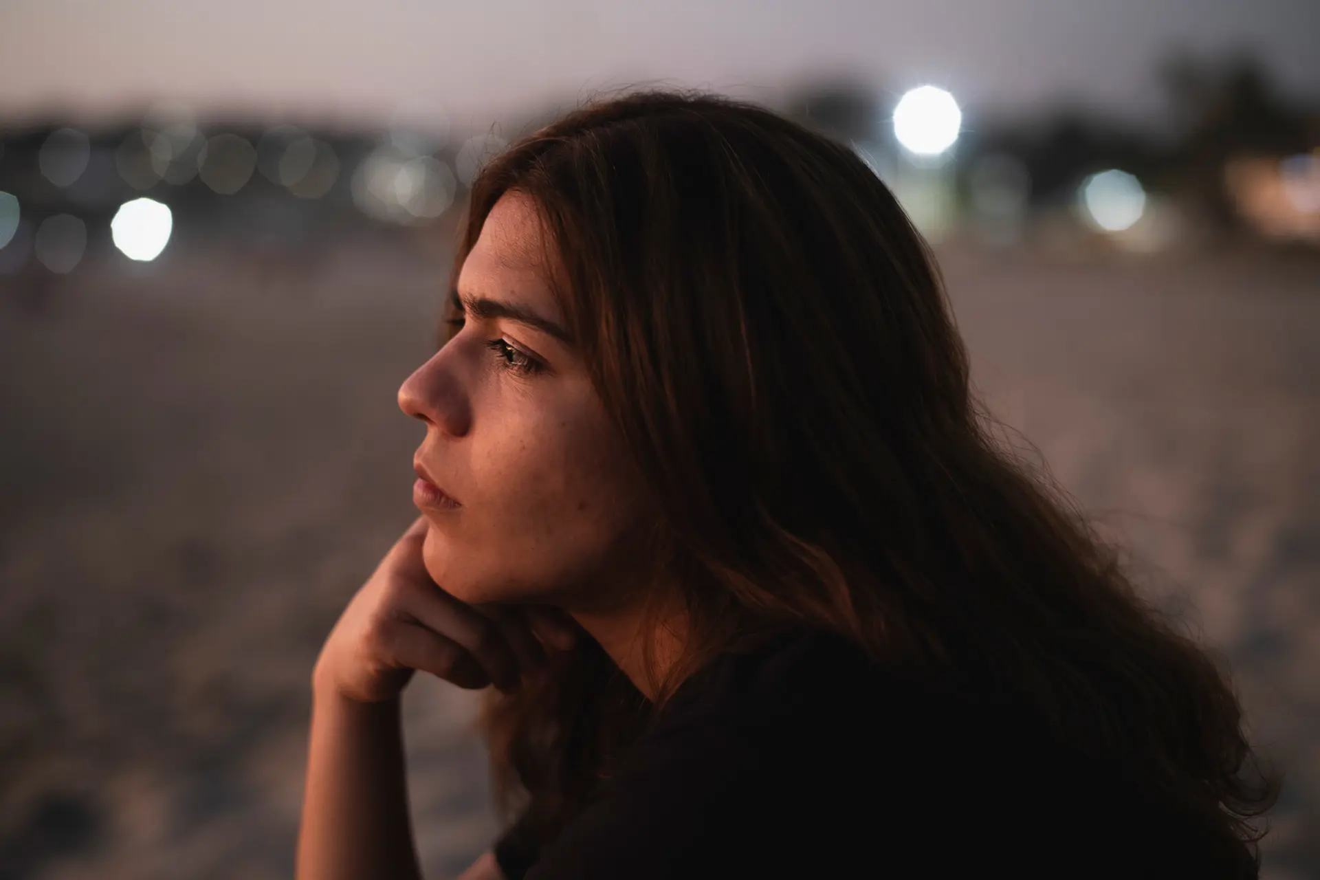 Close-up of a woman sitting thoughtfully on the beach
