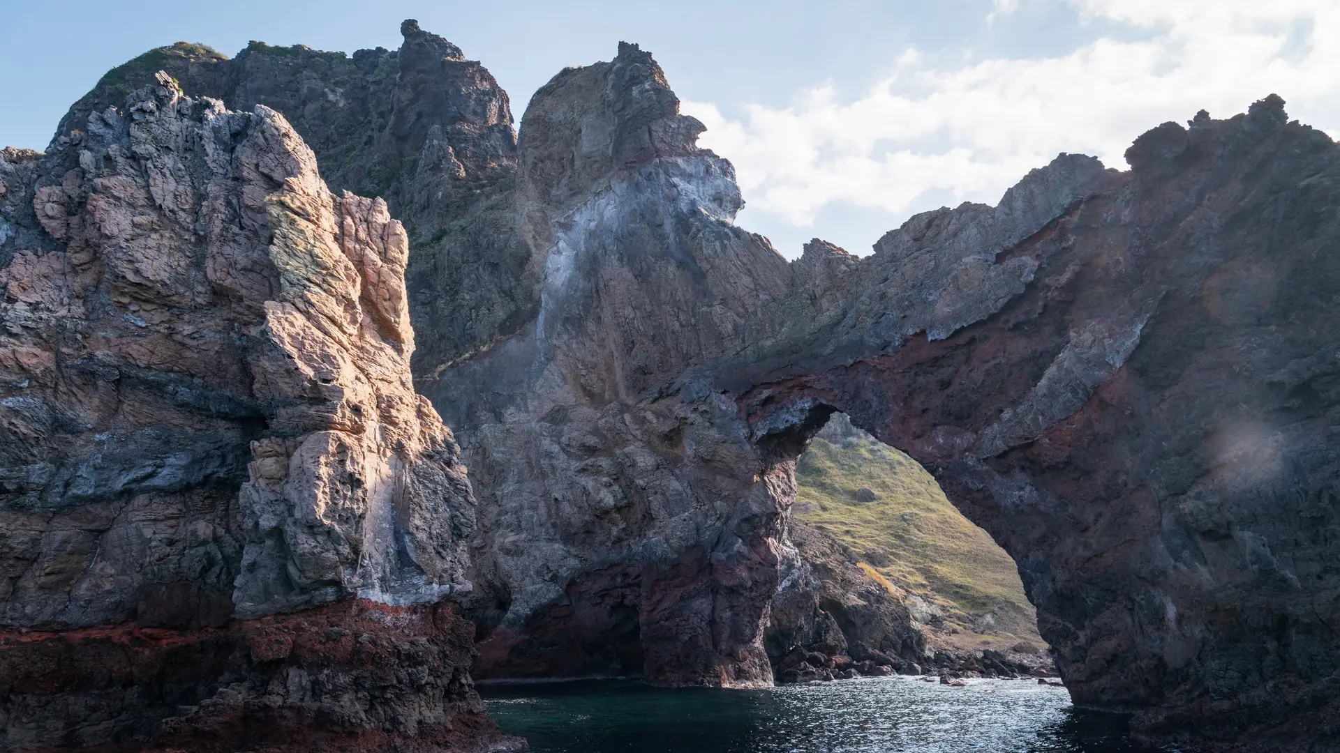 The rugged cliffs, dramatic arch, and interplay of light and shadow.