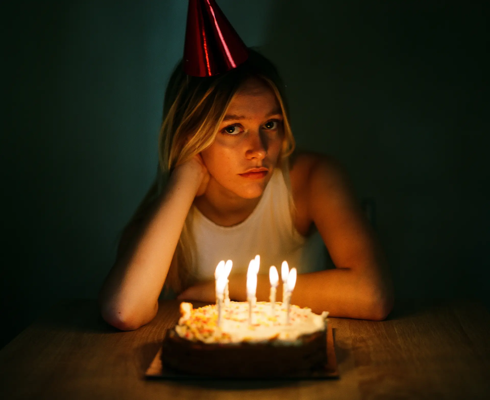 Sad woman sitting in front of her birthday cake with candles