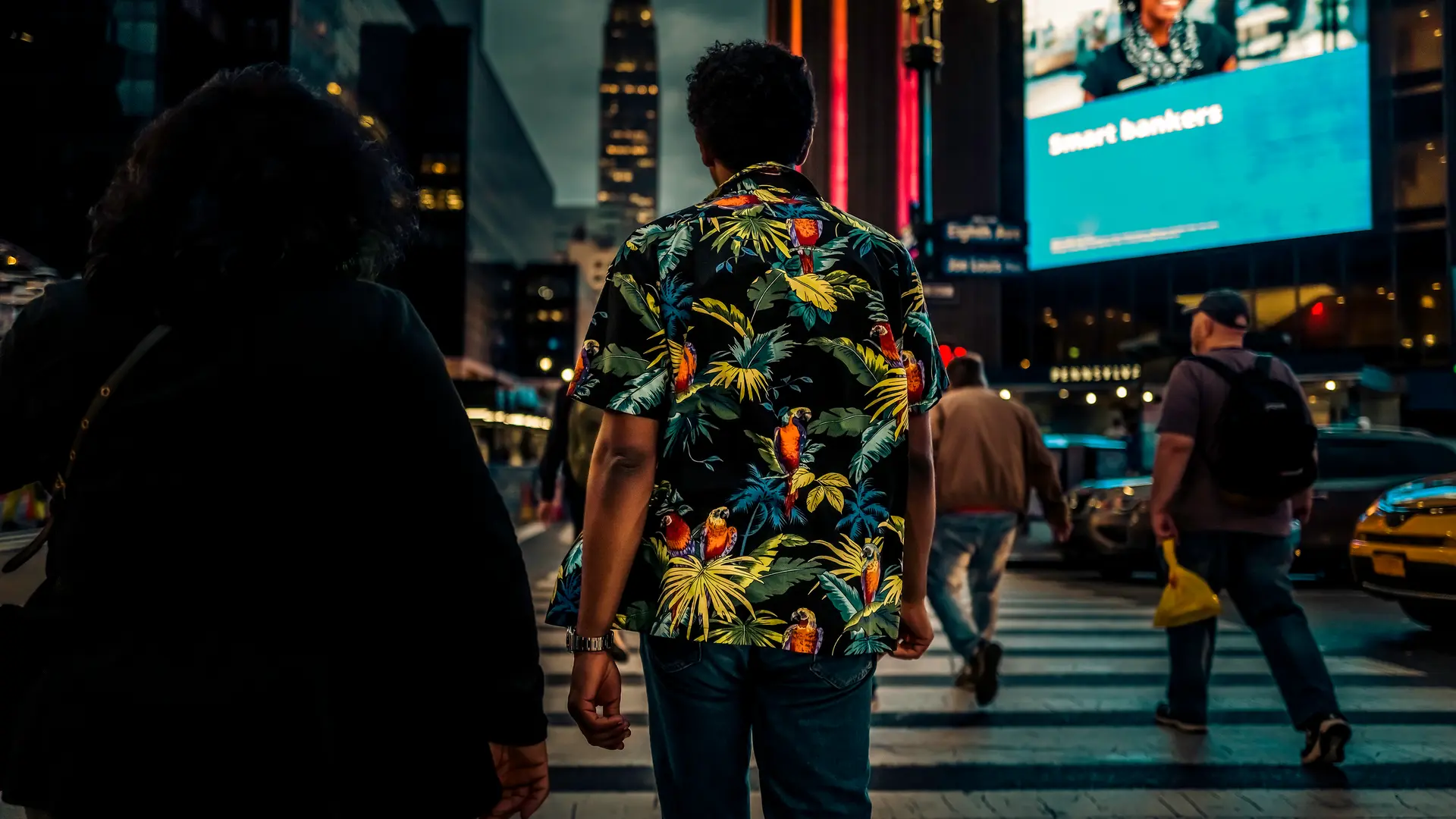 A man walking through a big city by night.