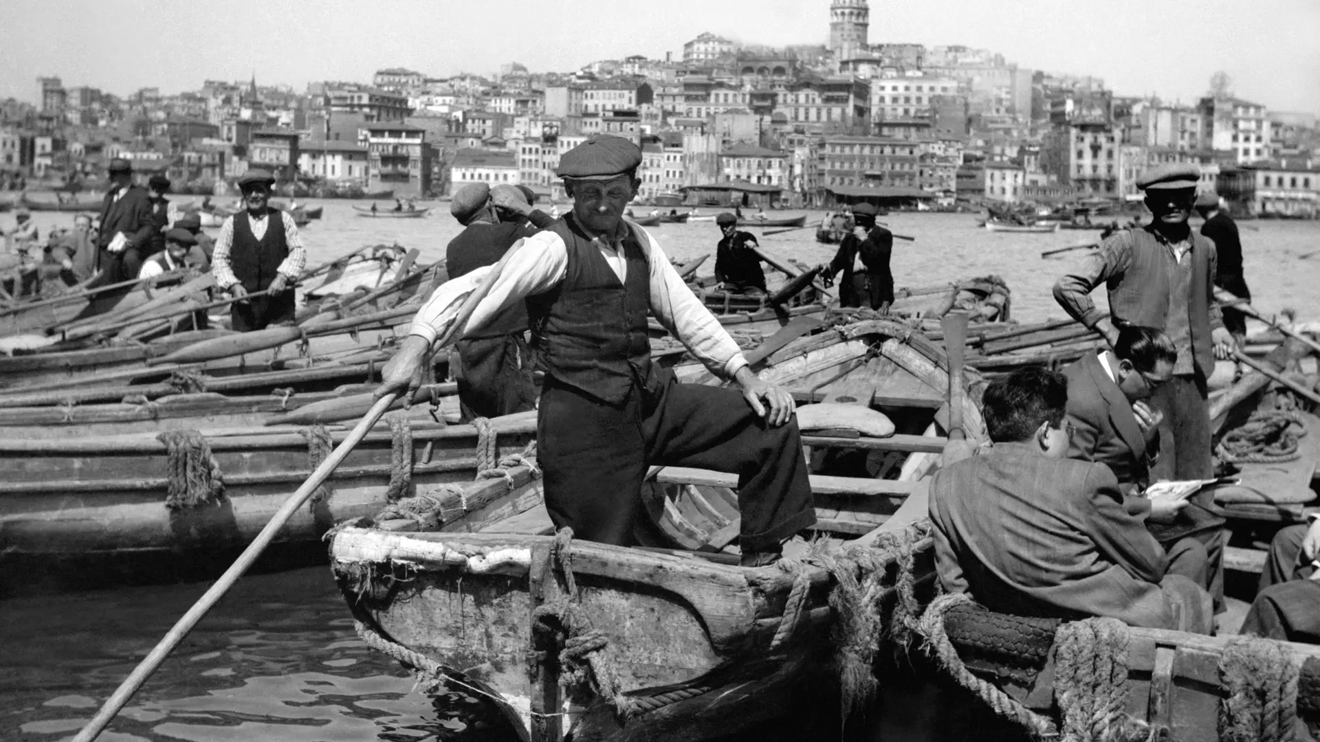Man standing in a fishing boat in a crowded harbour