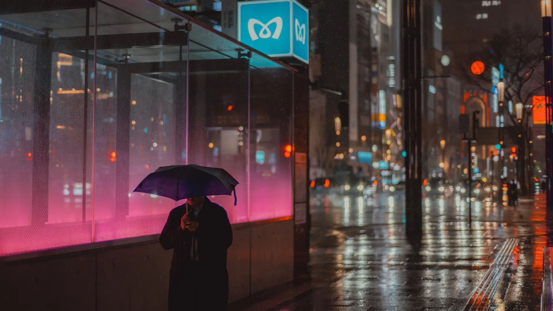 Man walks through rainy streets with umbrella