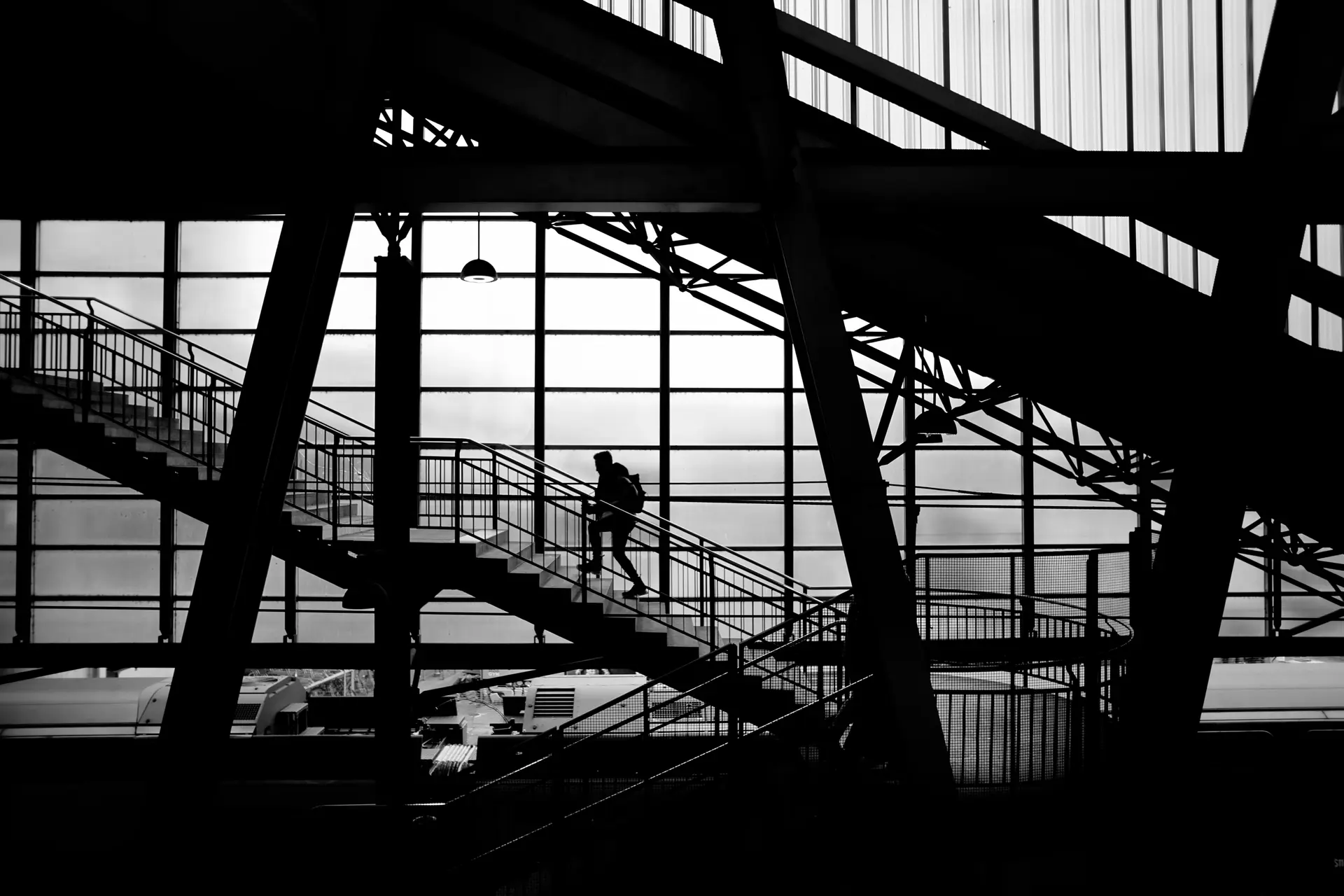 A man climbs the stairs of a railway bridge.
