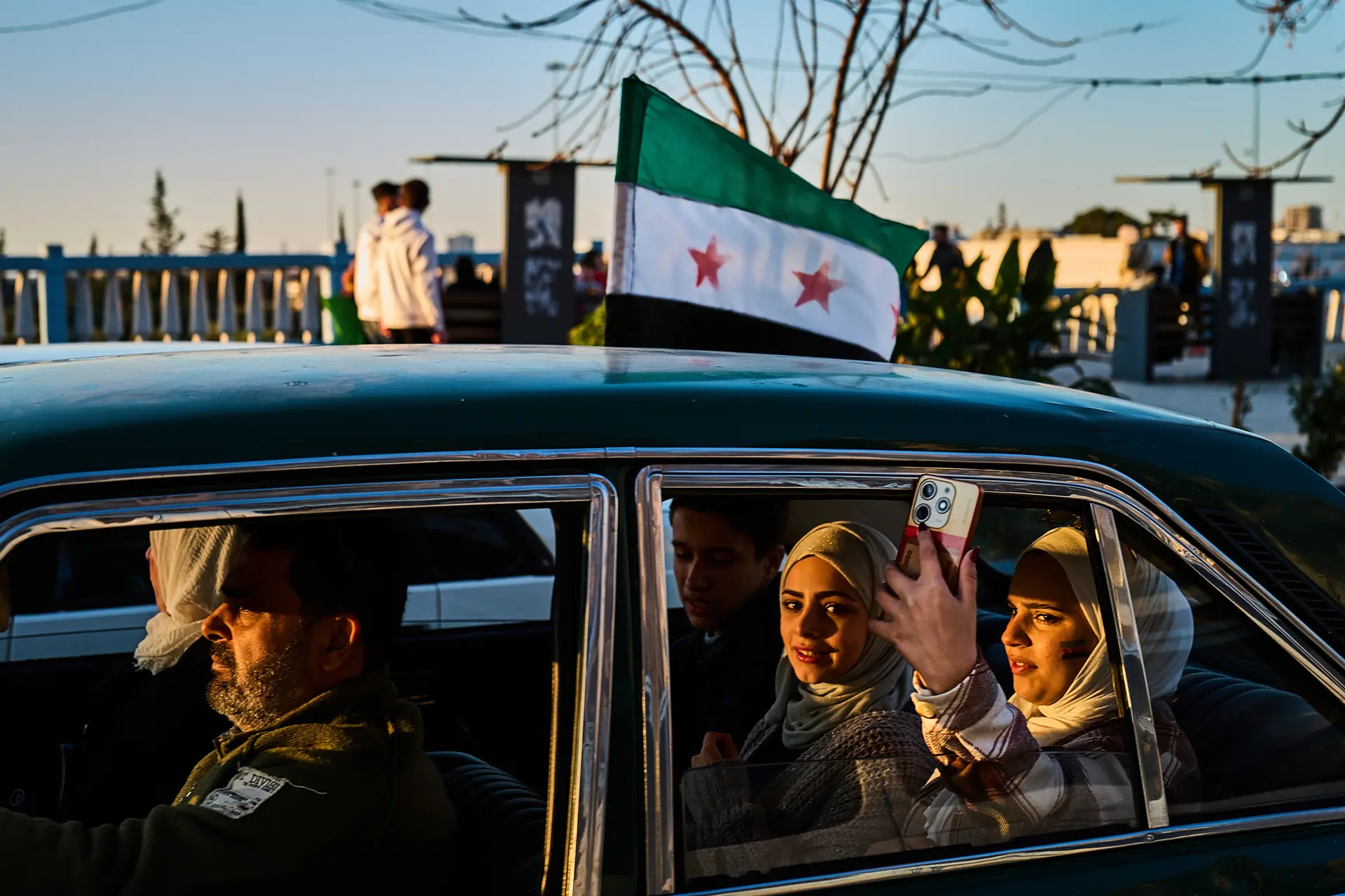 Women with headscarves in a car taking photos out of the window with a mobile phone