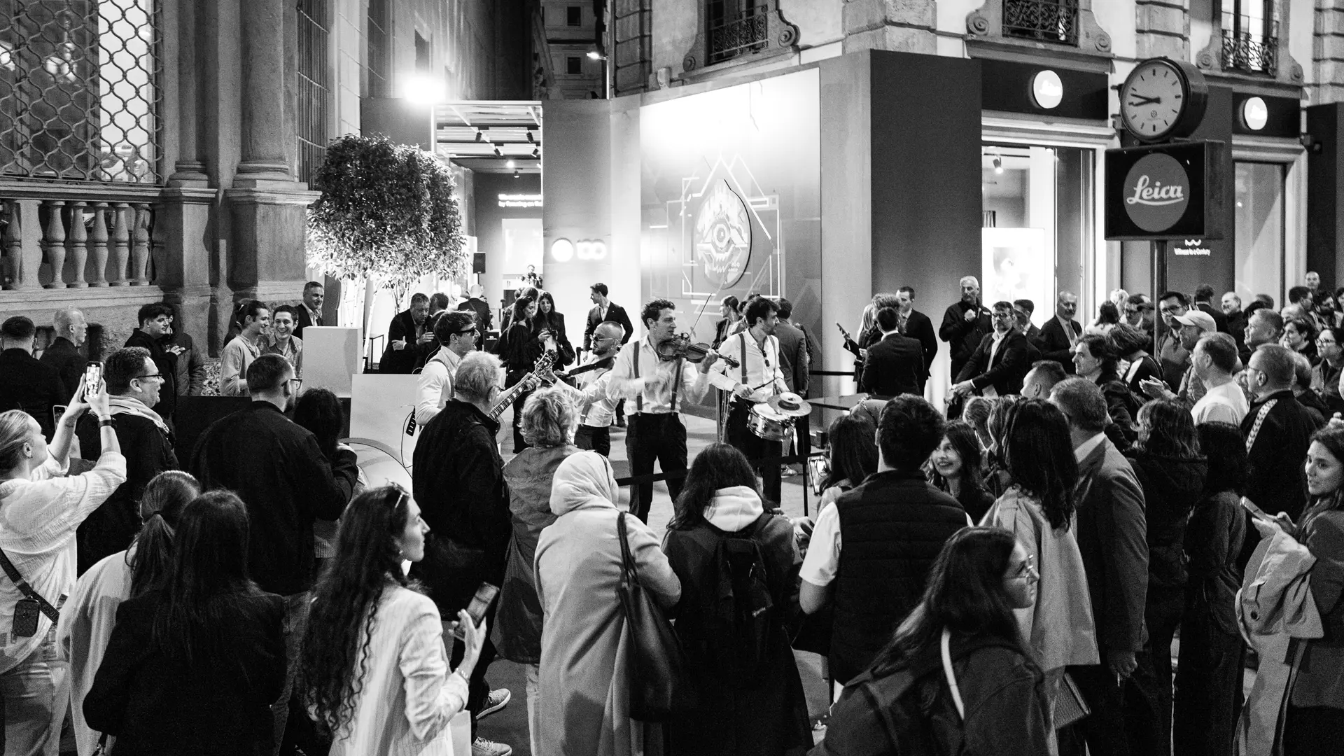 Guests at the celebrations stand in front of the Leica Store in Milan watching street musicians.