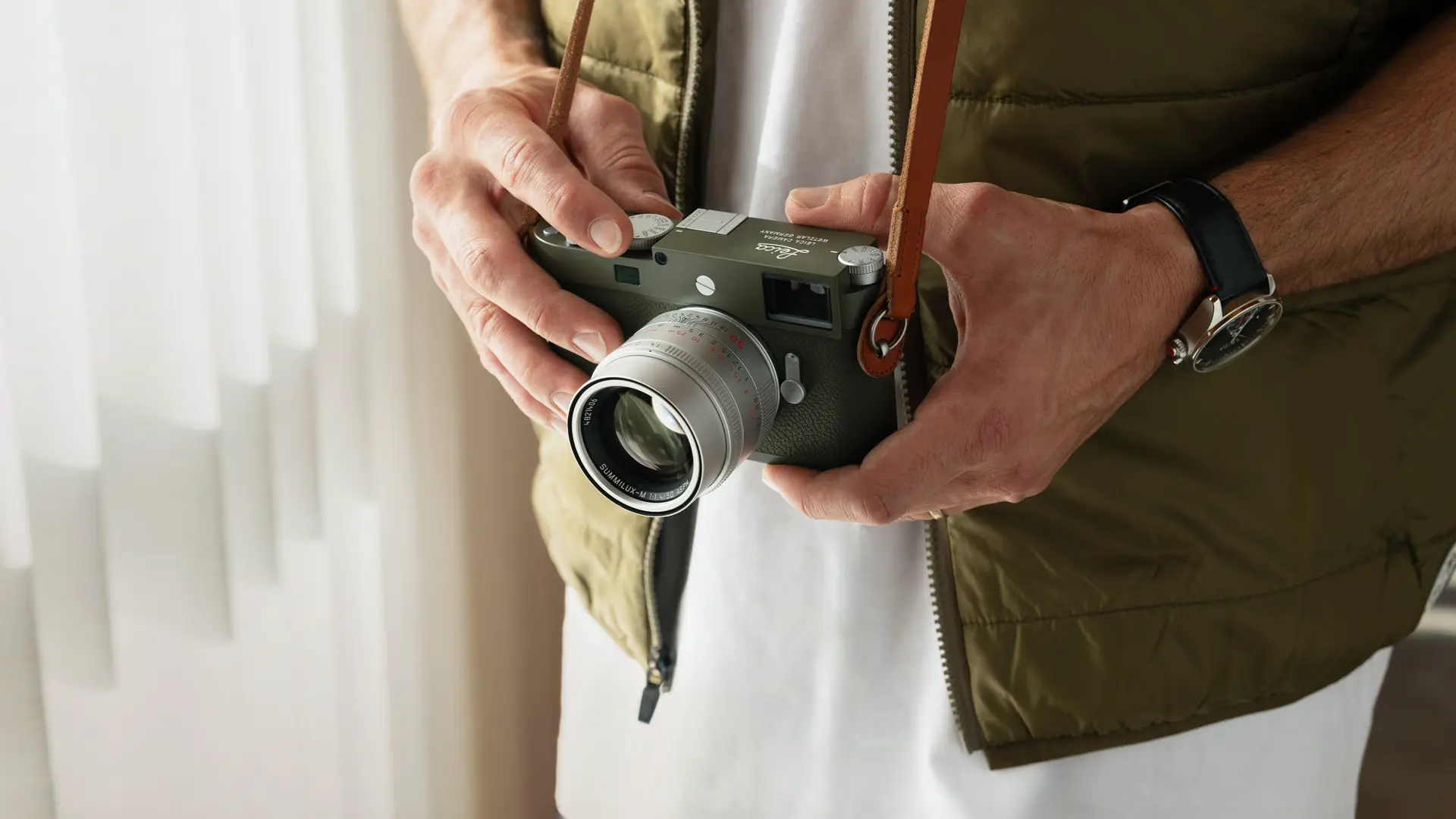 Leica M11-P with a silver lense and cognac strap in hands