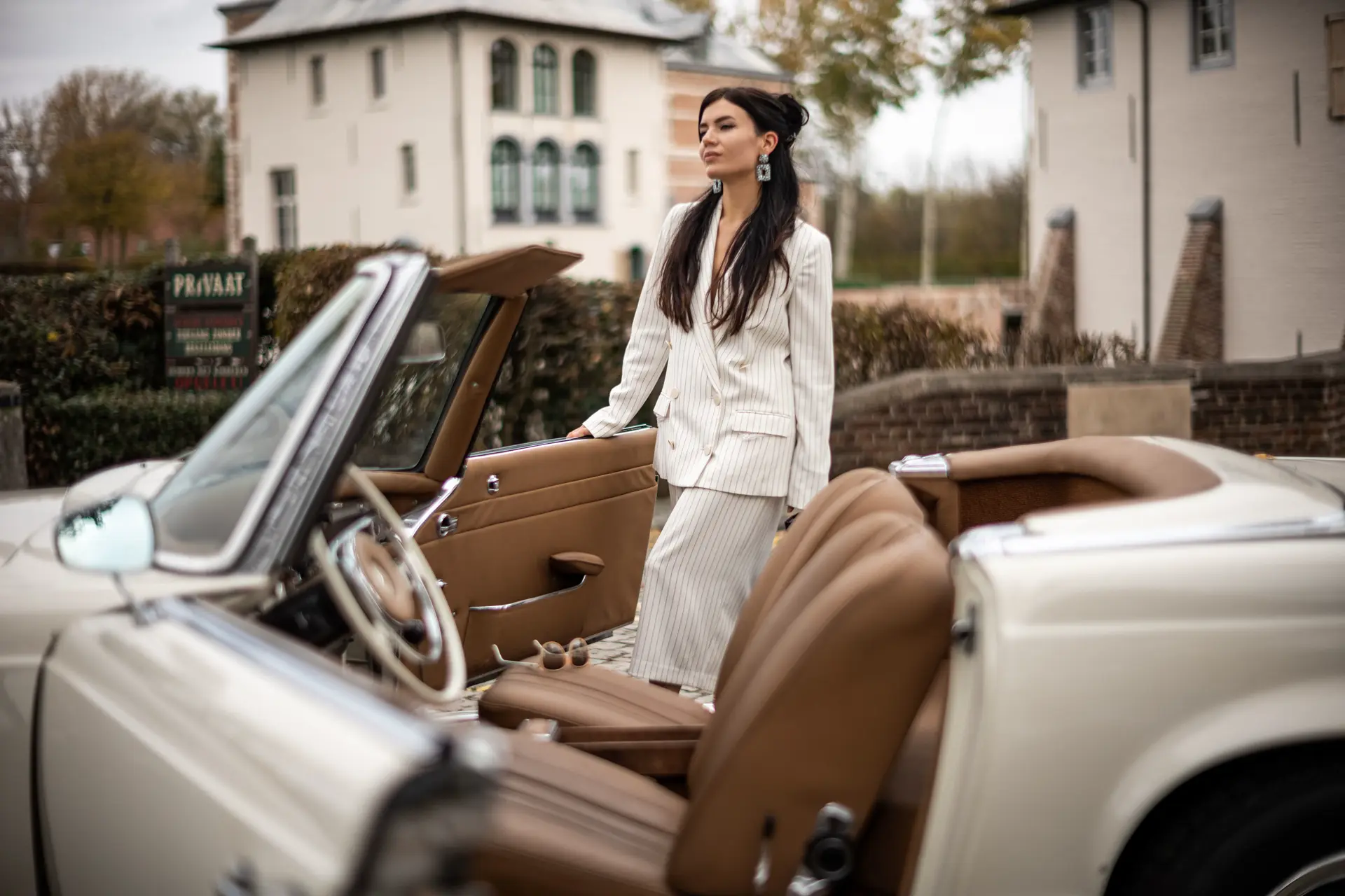 woman with brown long hairs stand beside a oldtimer cabrio