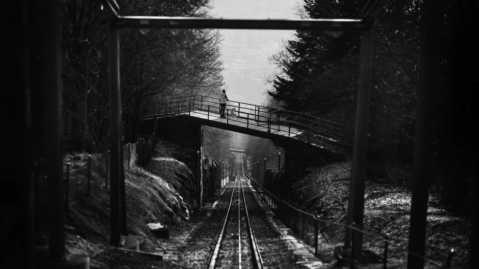 A picture of a person crossing a bridge under which the Magglingen cable car passes