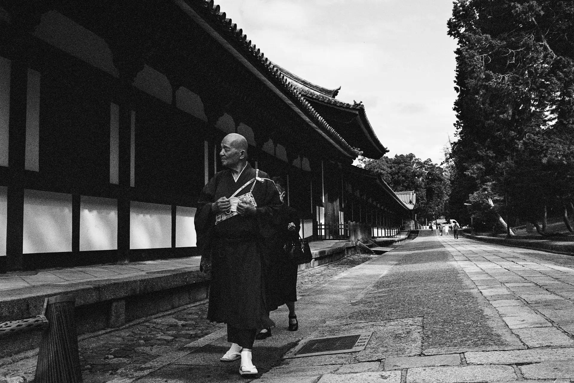 A man is walking down a street along few houses in Japan.