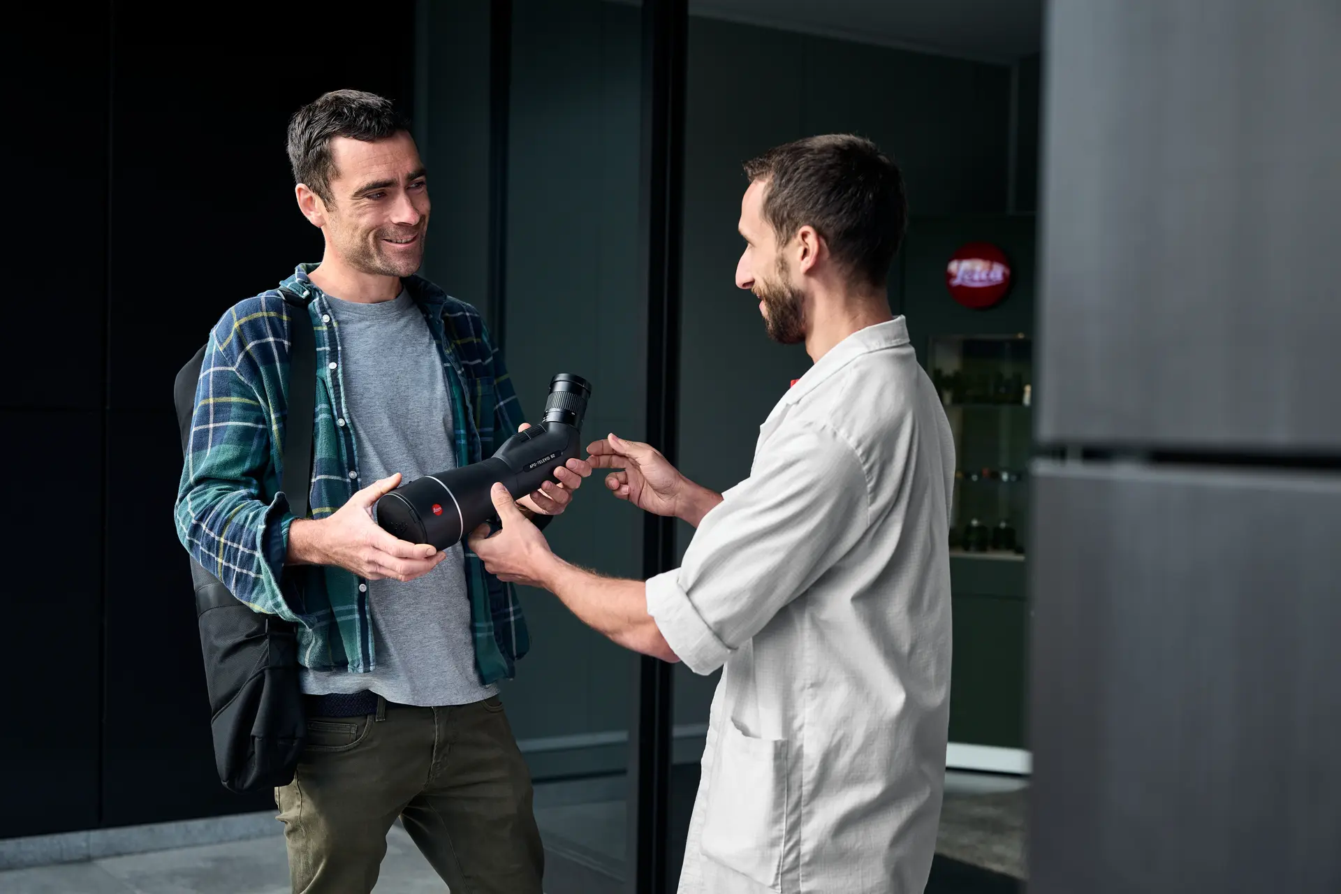 A man hands a Leica APO-Televid spotting scope to a customer