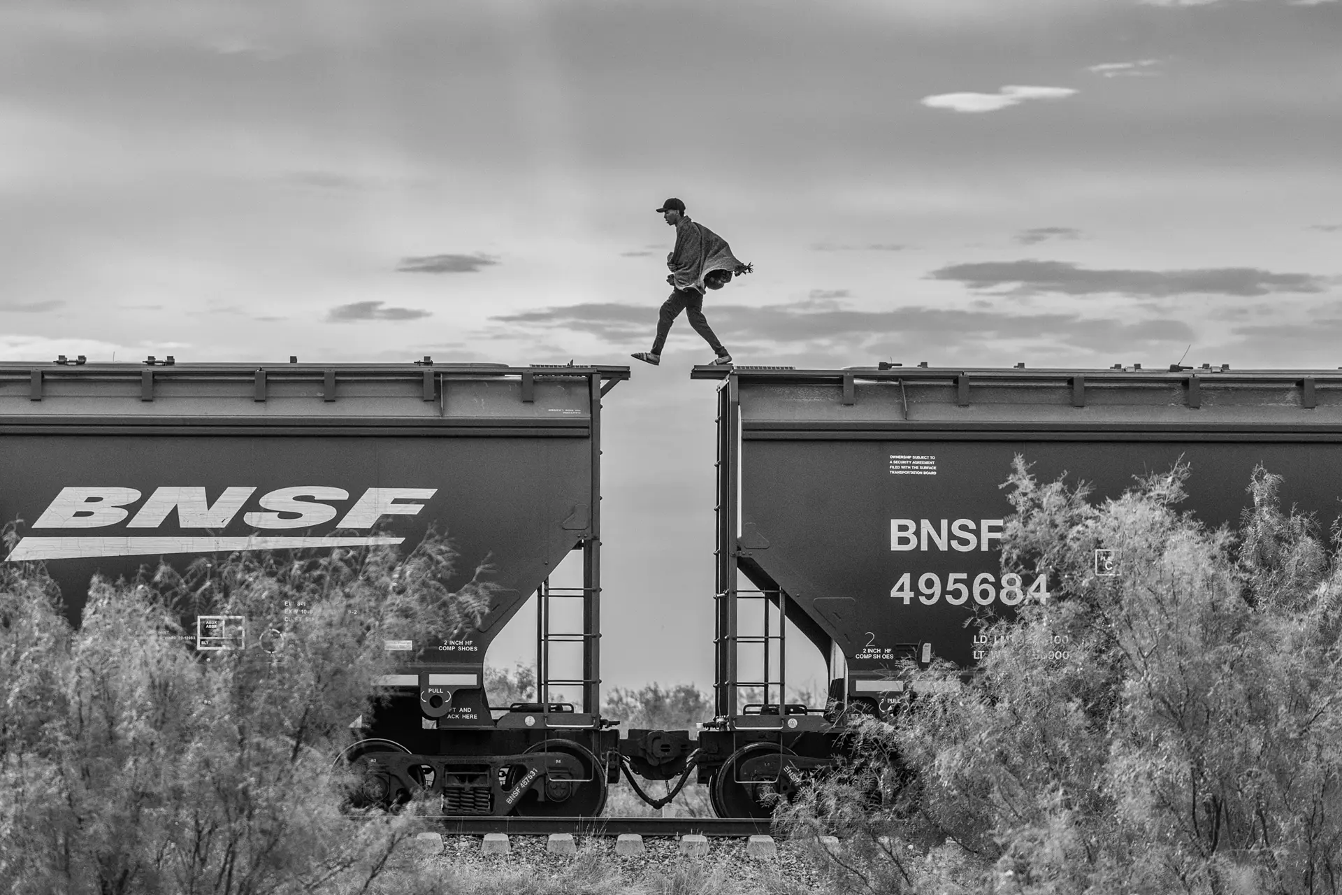 A man jumping from on train carriage to another.
