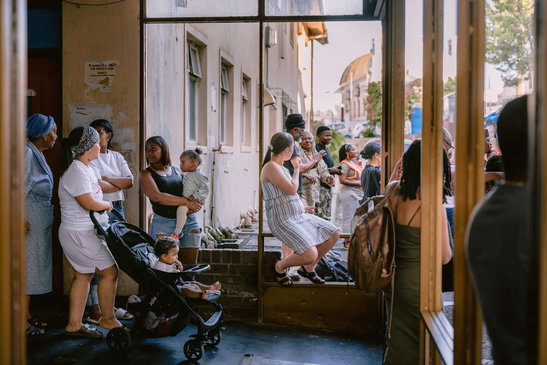 Many people standing and sitting inside a house and in front of.