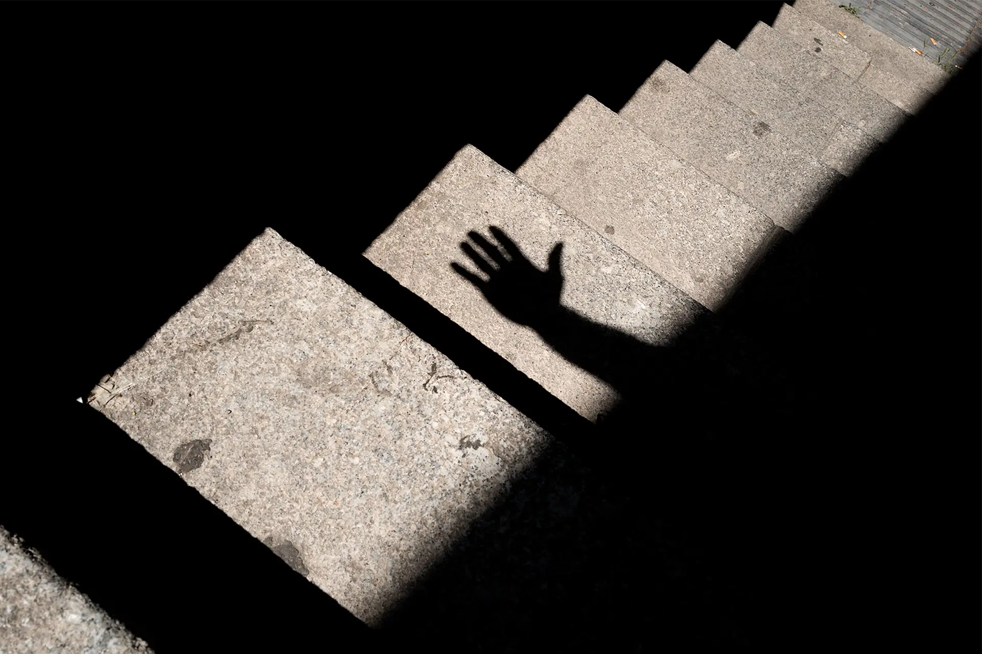 Shadow of a hand on a grey staircase