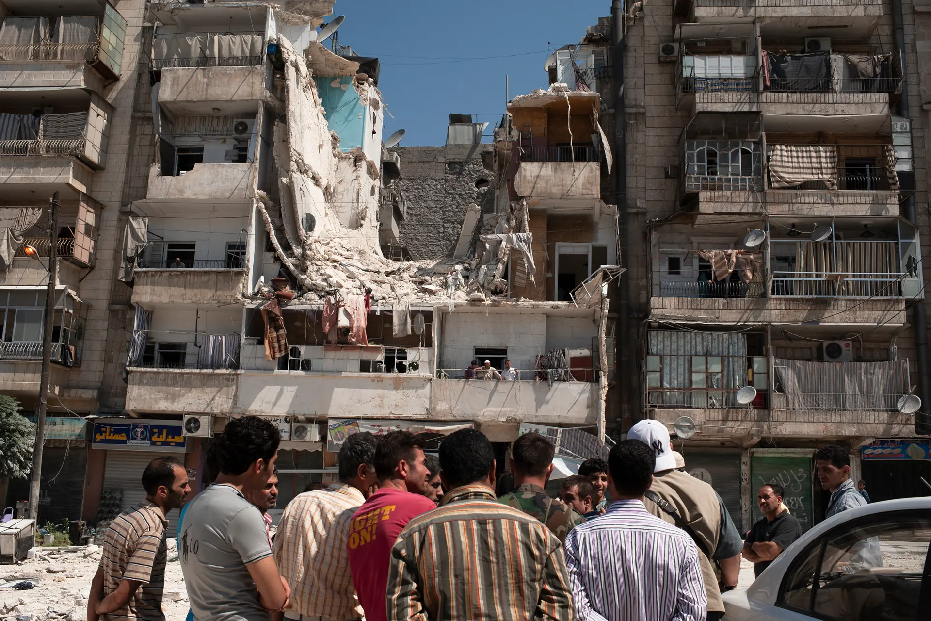Menschen stehend vor Ruinen aus dem Syrienkrieg