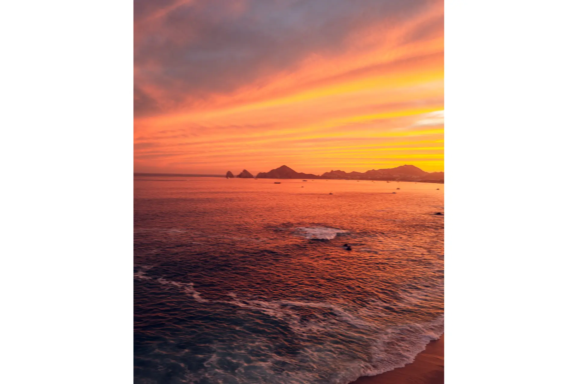 Sea illuminated red by the sunset with mountains in the background