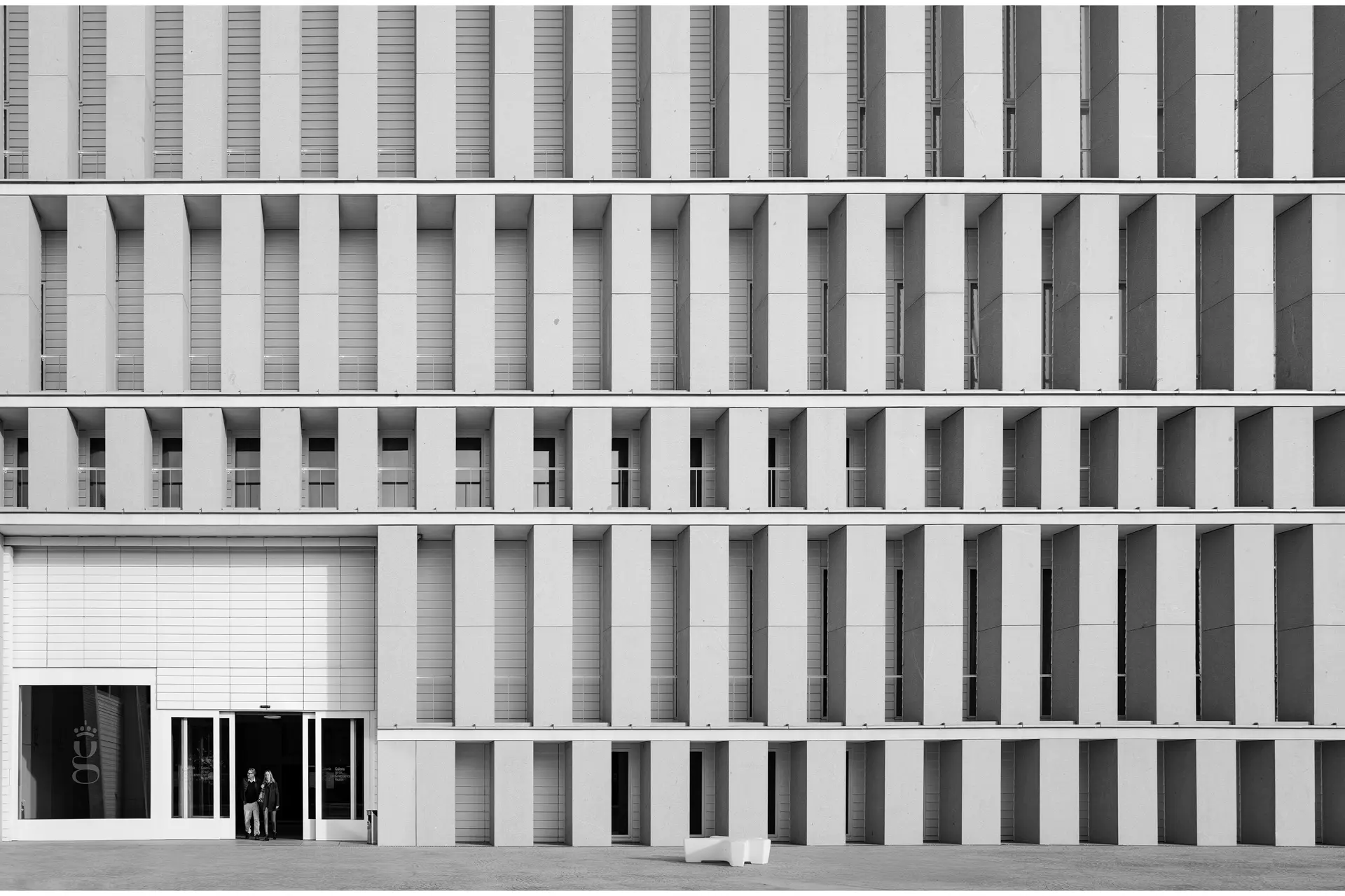 Fachada de edificio blanco con gente en la puerta