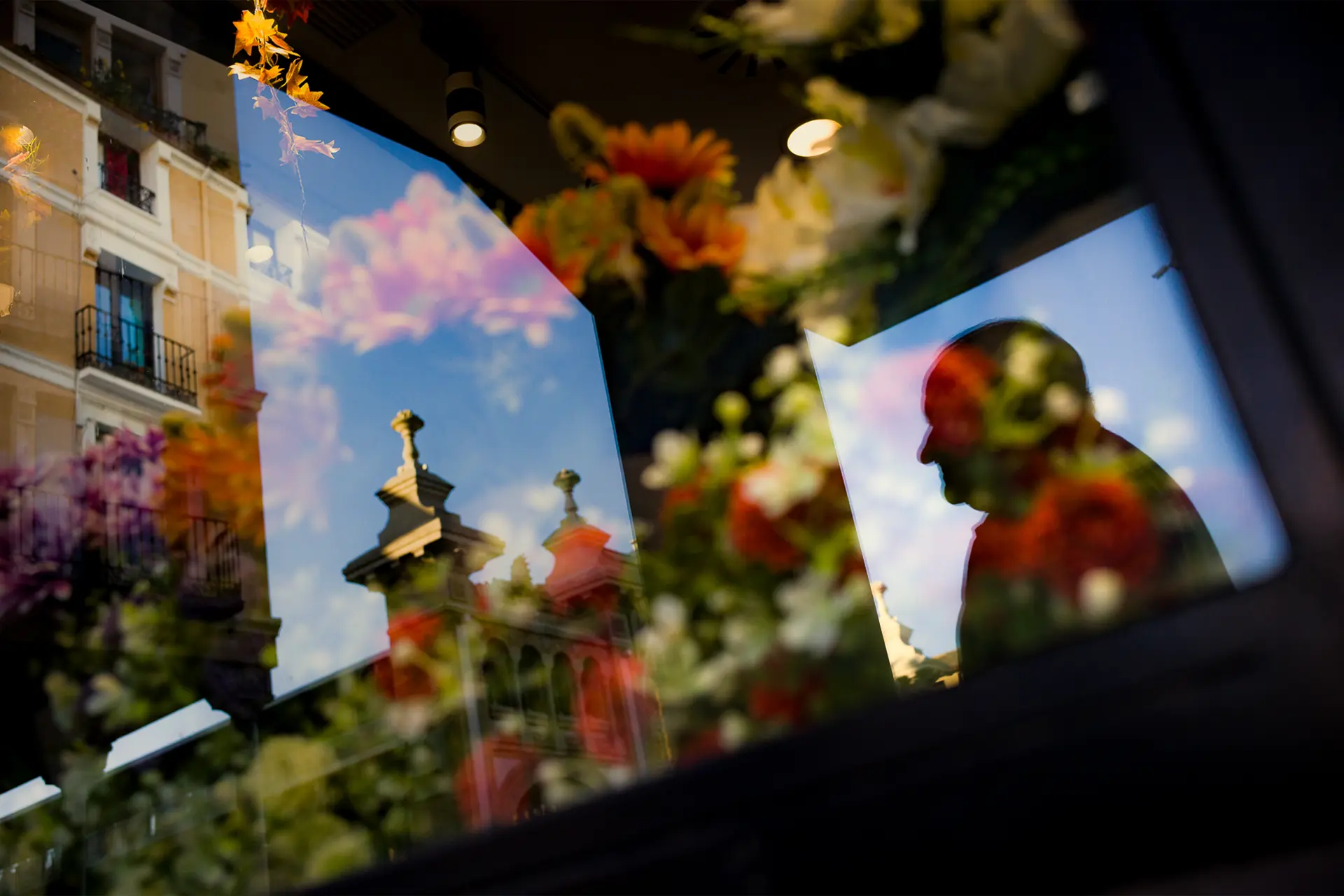 Reflejo en cristal de hombre, edificio y flores