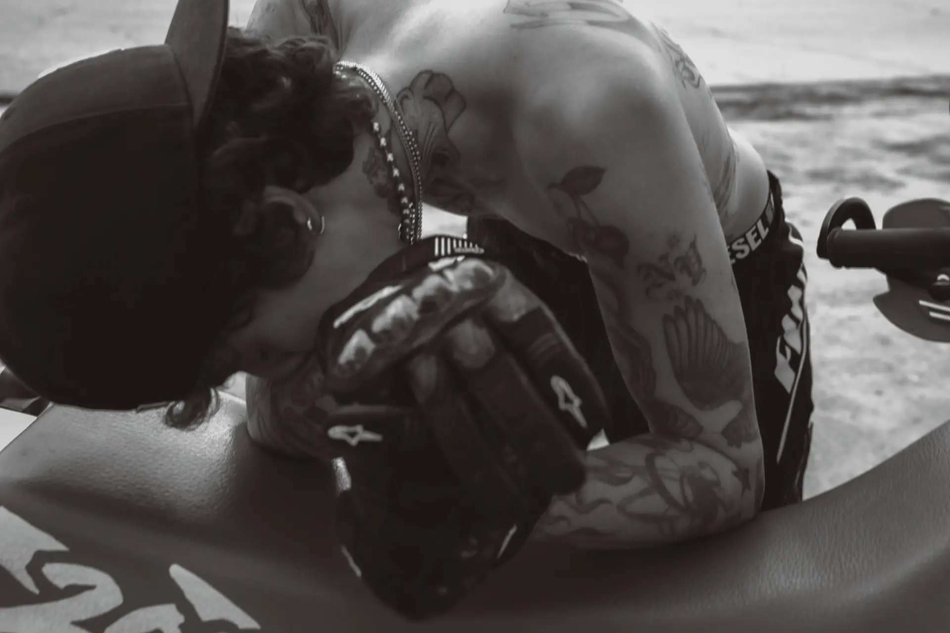 Black and white photograph of a biker leaning on their bike