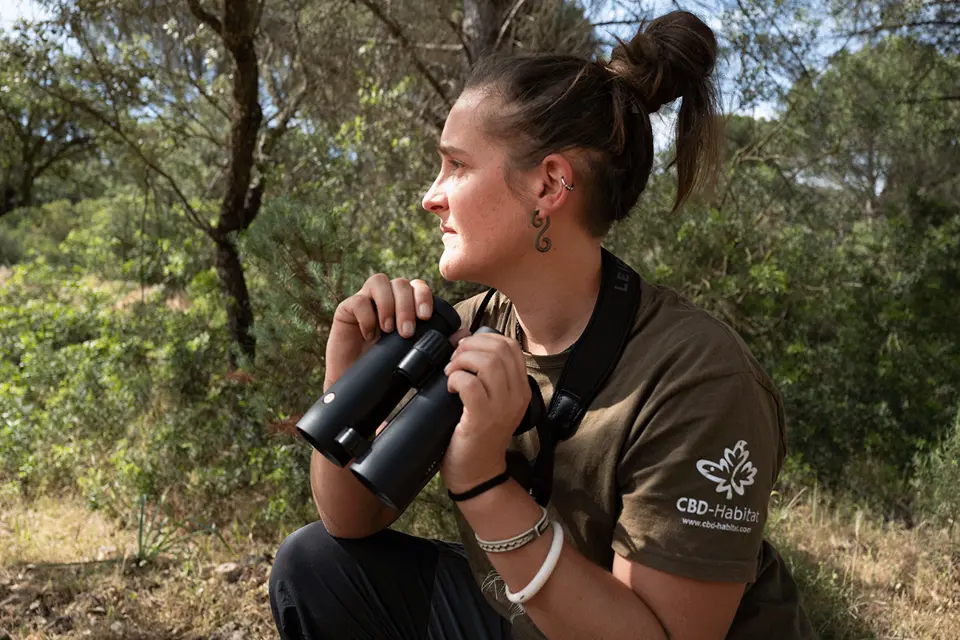 Carmen Rueda holding a pair of Leica binoculars. 