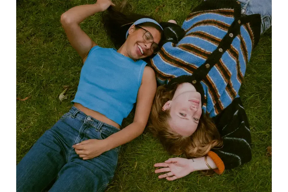 Portrait of two women laying in grass. 